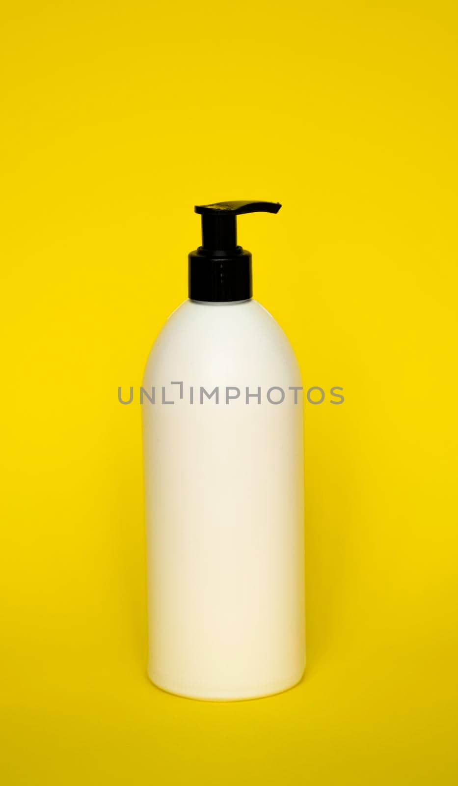 White plastic soap dispenser pump bottle isolated on yellow background. Skin care lotion. Bathing essential product. Shampoo bottle. Bath and body lotion. Fine liquid hand wash. Bathroom accessories. by vovsht