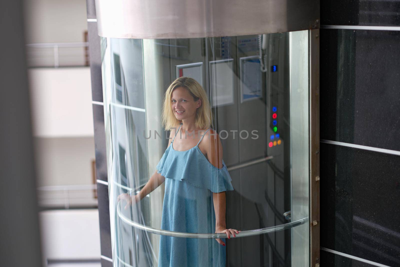 Beautiful smiling woman in transparent glass elevator. Stylish modern elevators in hotels and business centers concept