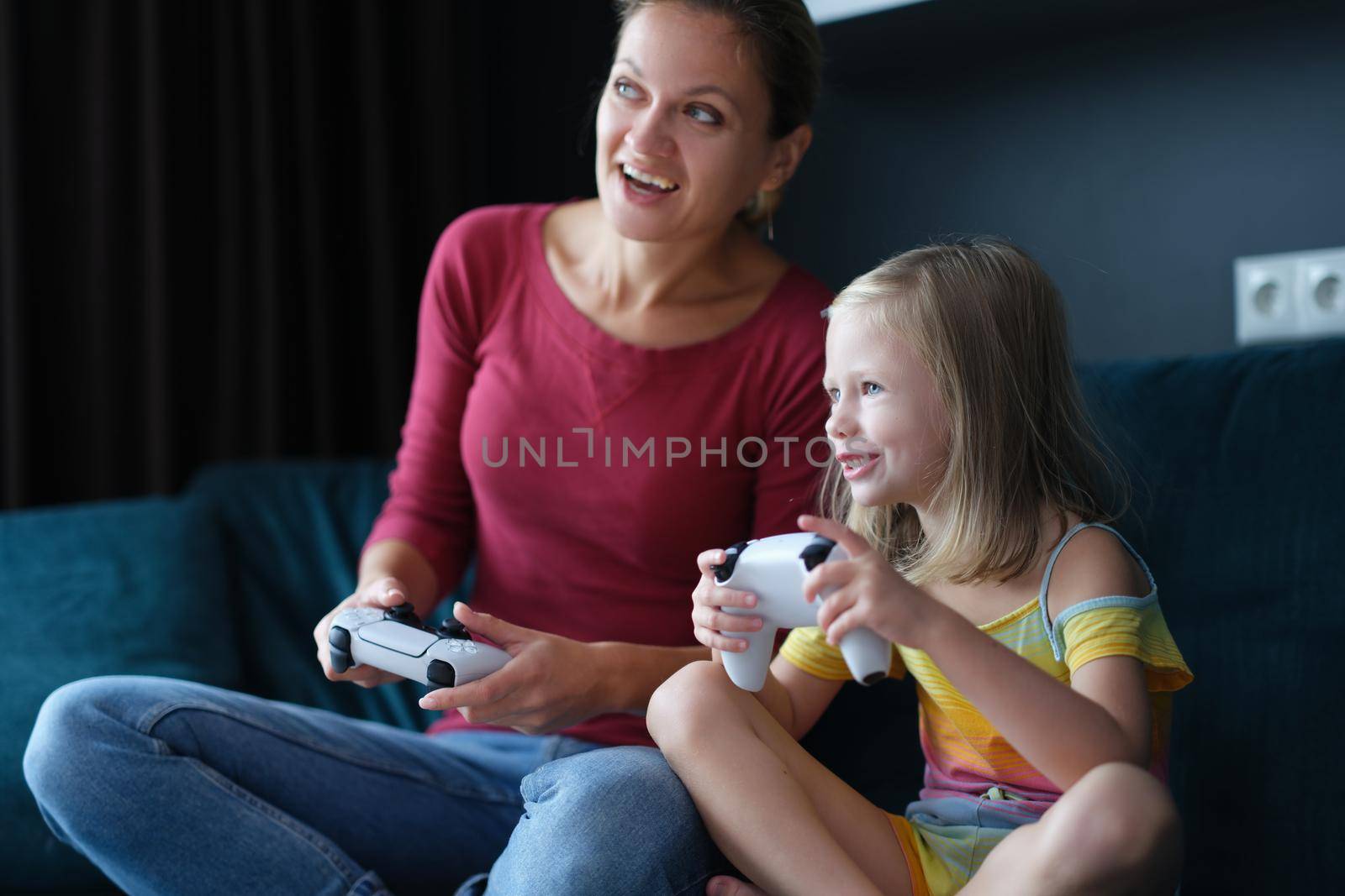 Mother and baby girl playing video games. Happy family together and having fun at home playing online games