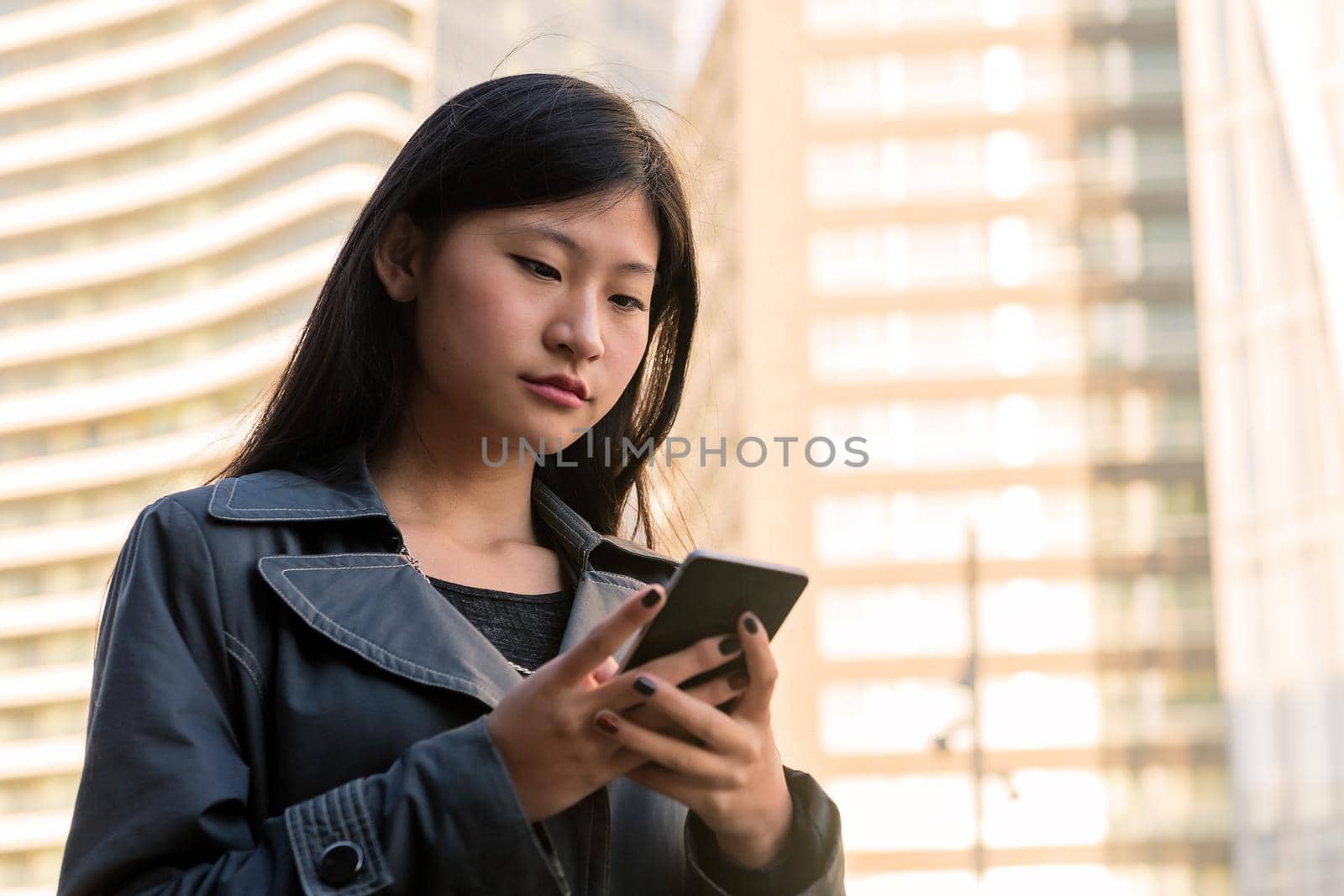 elegant young asian woman consulting her mobile phone in the city, technology and urban lifestyle concept, copy space for text