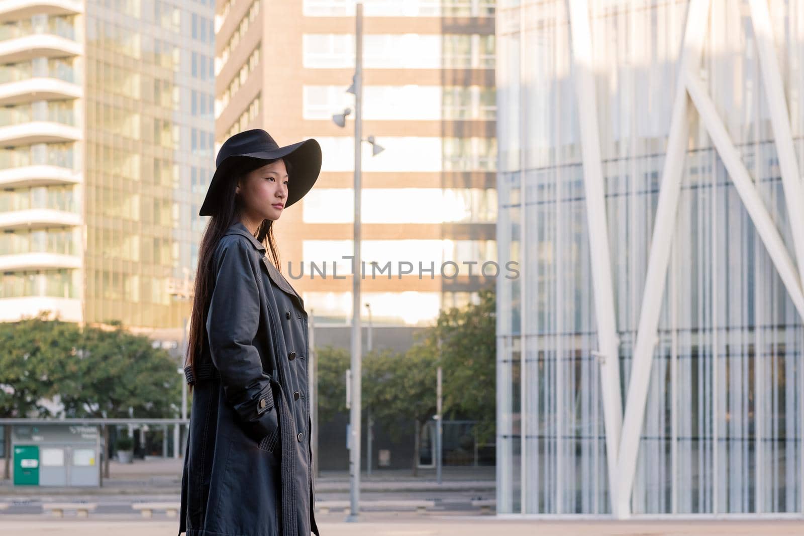 elegant asian woman in hat and trench coat walking downtown, urban lifestyle concept, copy space for text