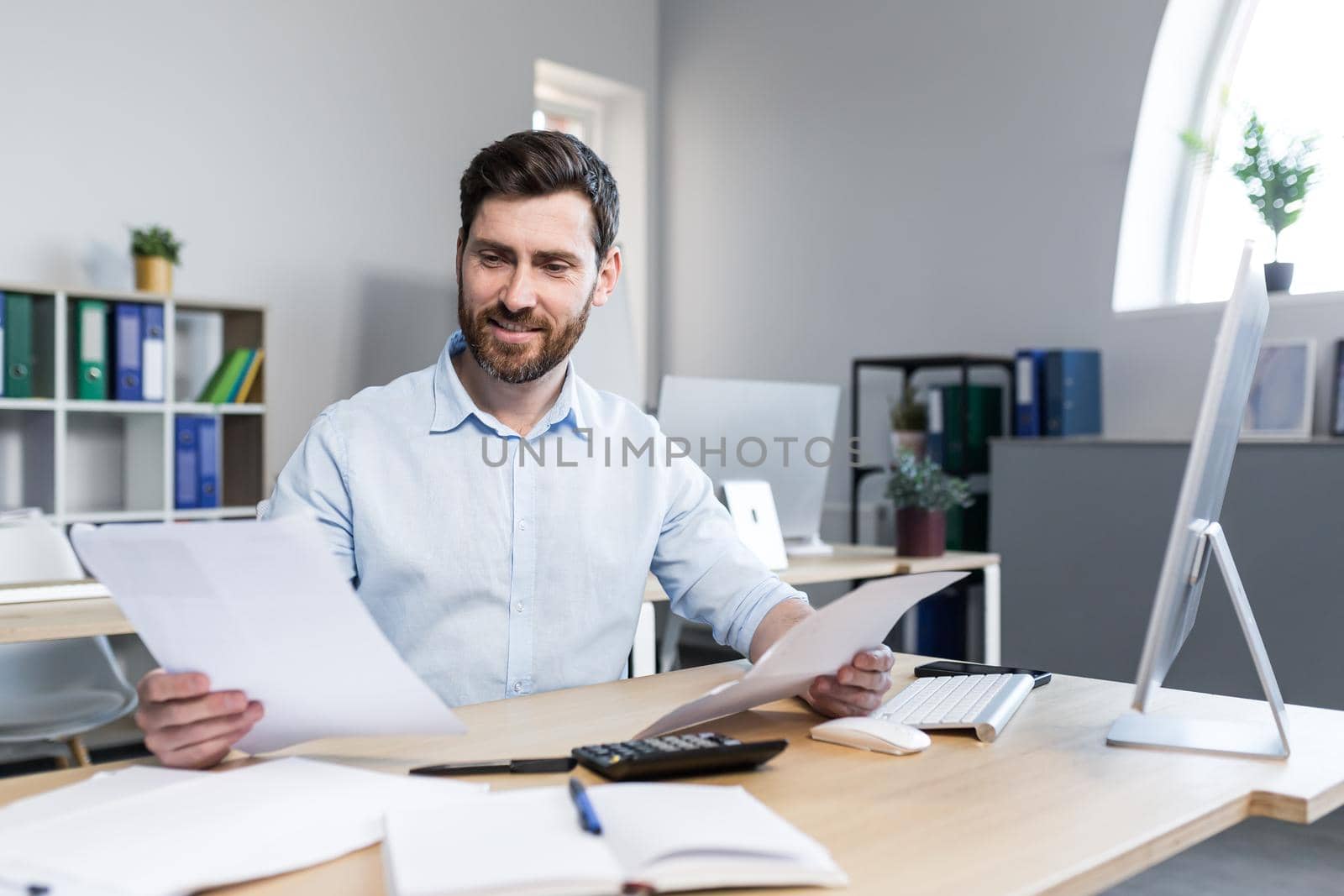 Happy businessman at paper work, examining financial documents, man at work working in the office by voronaman
