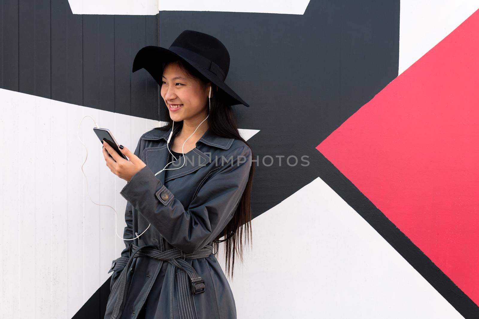 smiling young asian woman with earphones and smart phone, concept of technology and modern lifestyle, copyspace for text