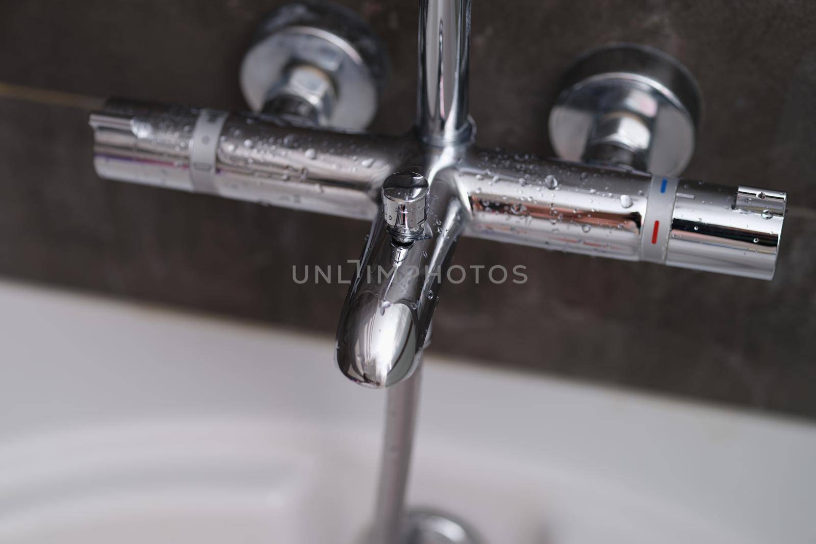 Chrome faucets on white ceramic bathtub in bathroom. Water drops on the faucet in bathroom concept