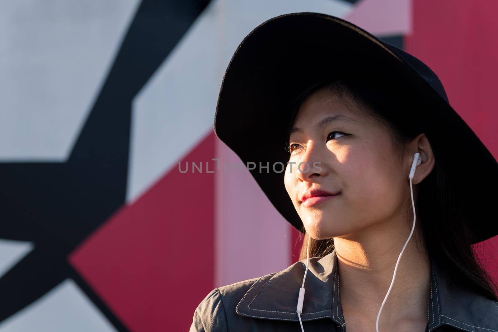 young beautiful classy chinese woman with earphones listening music, concept of technology and fashion lifestyle