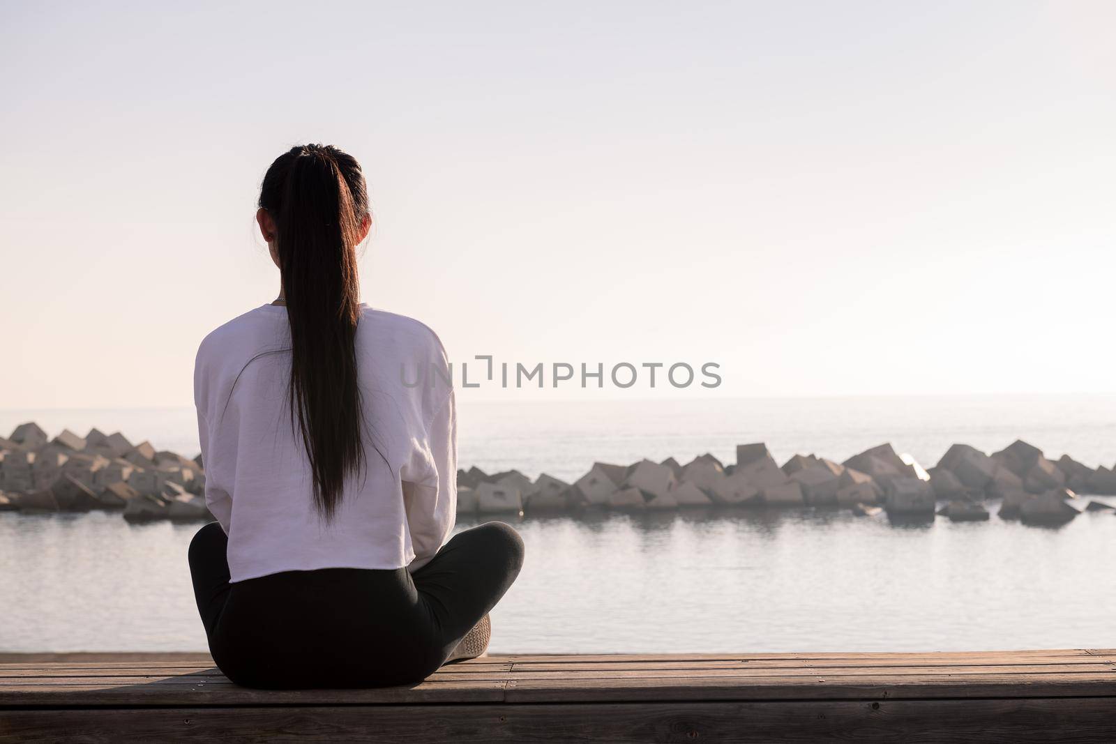 rear view of a young woman sitting meditating by raulmelldo