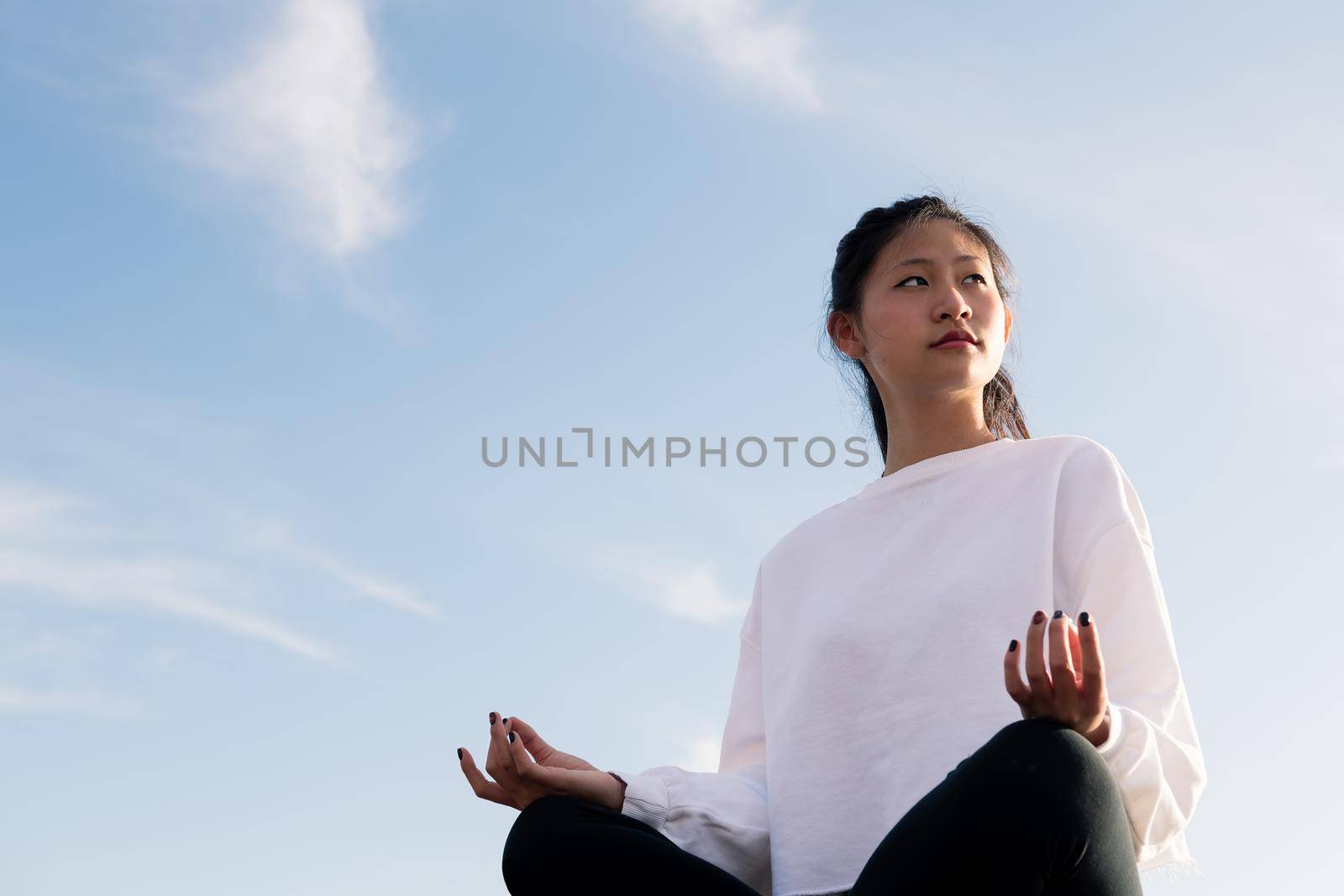 beautiful young asian woman sitting meditating at sunrise, concept of relaxation and mental health, copy space for text