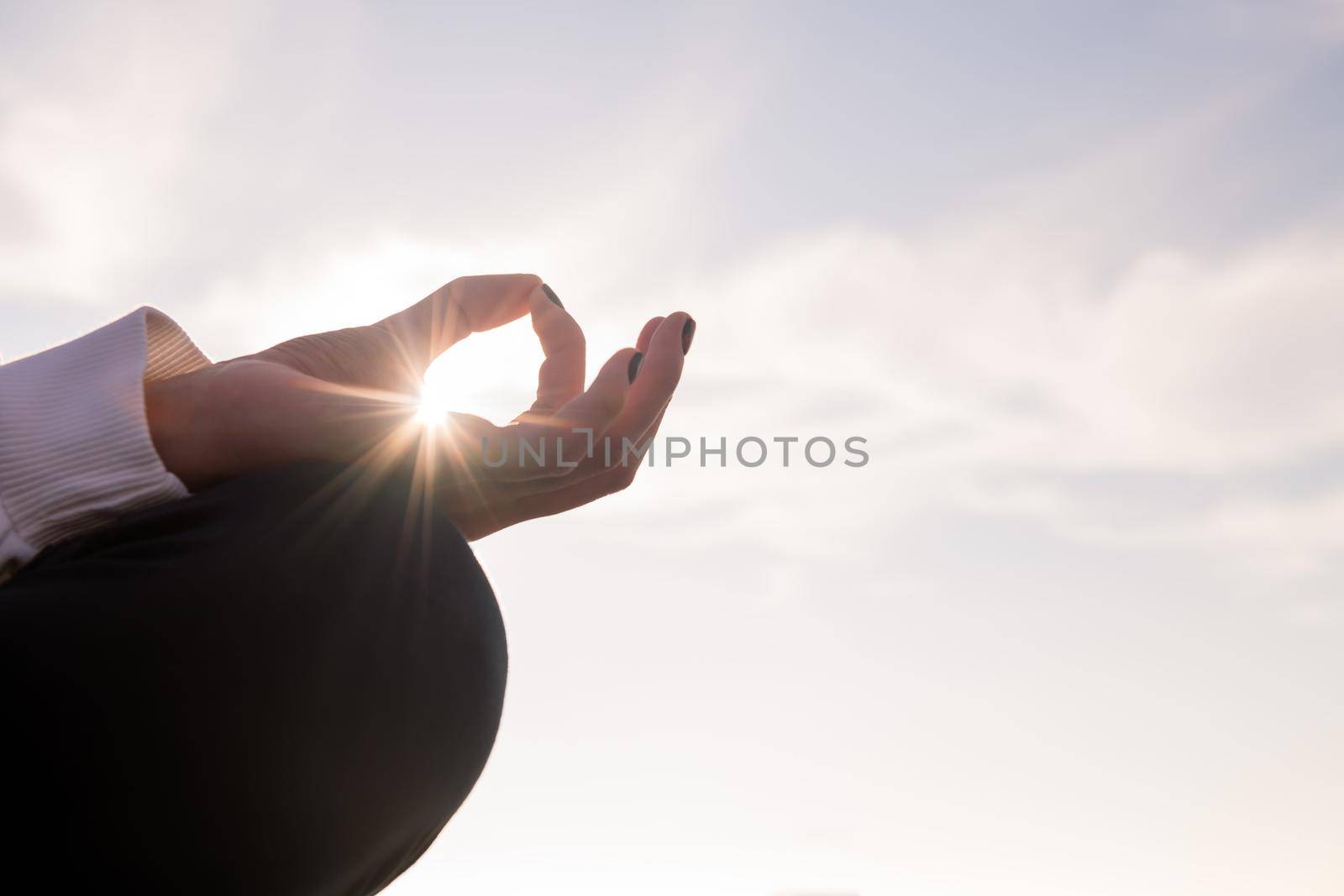 hand with sun beams of a woman meditating by raulmelldo