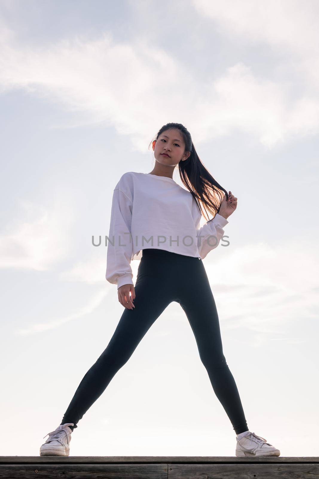 vertical photo of a powerful oriental sportswoman posing confident looking at camera, concept of sport and healthy lifestyle, copyspace for text