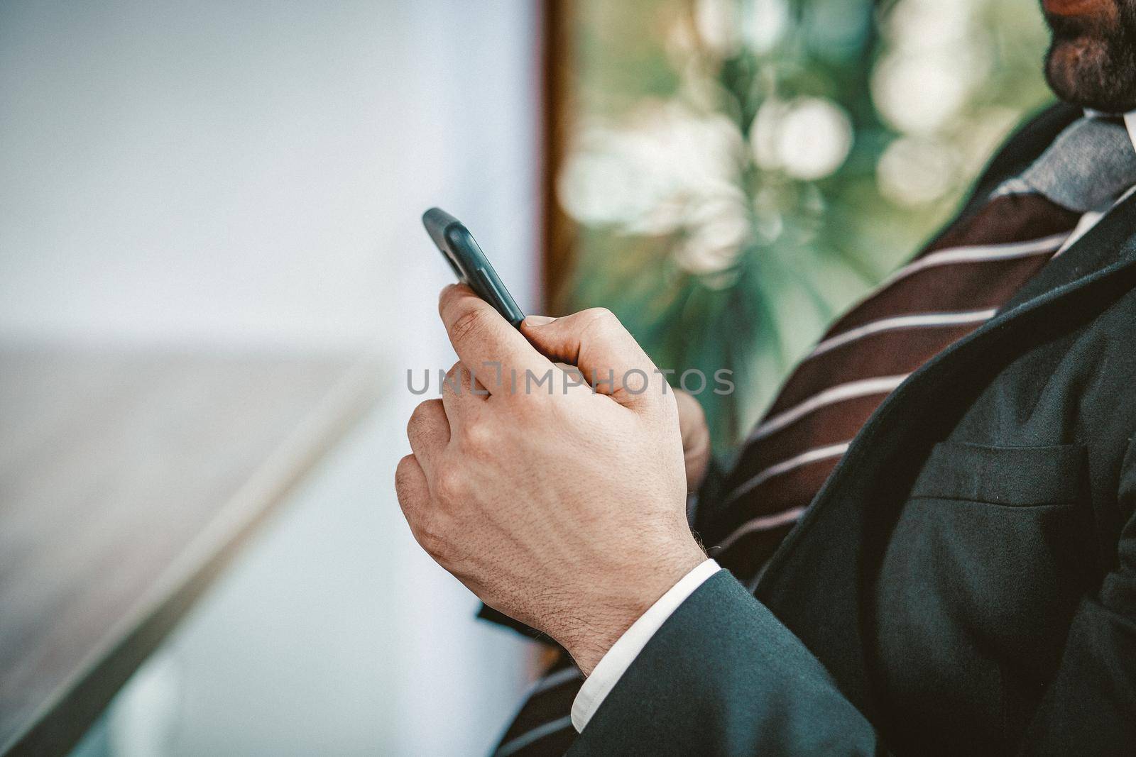 Business Man using Smart Phone, Close Up hands Of Caucasian Man In Dark Suit And Tie Typing Or Reading On Phone Online During Coffee Break In Office, Toned Image