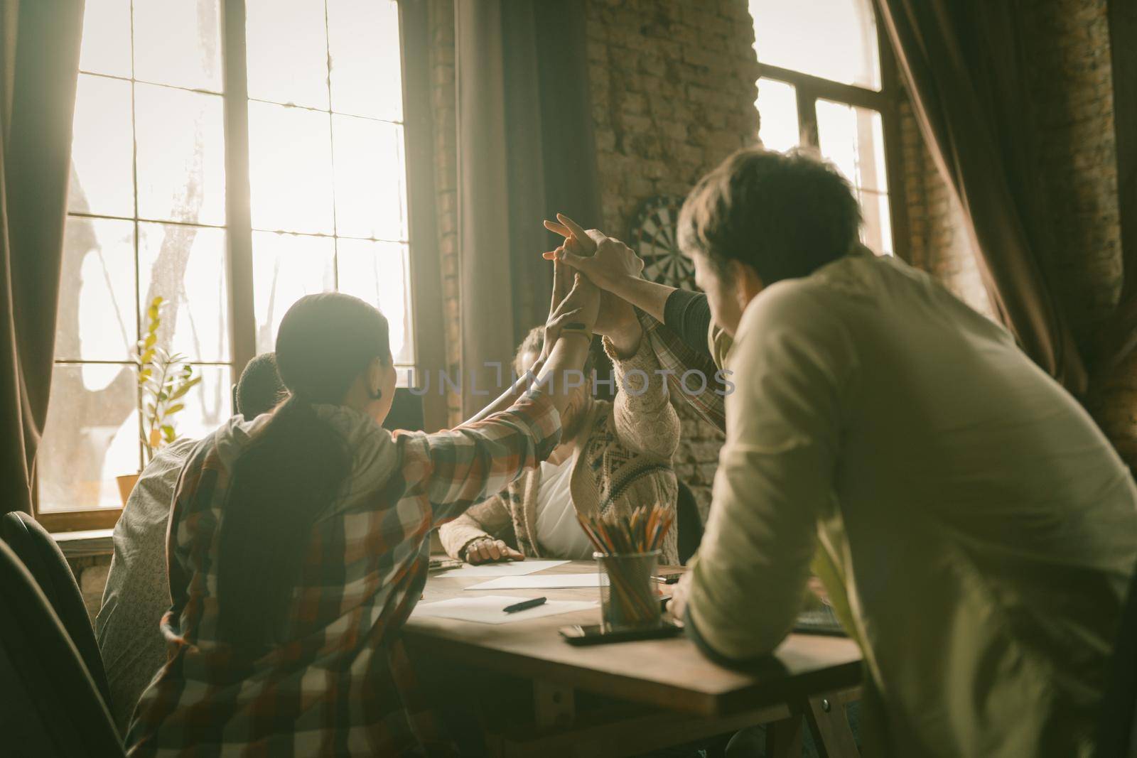 Friendly Team Joining Their Hands In High Five Gesture by LipikStockMedia