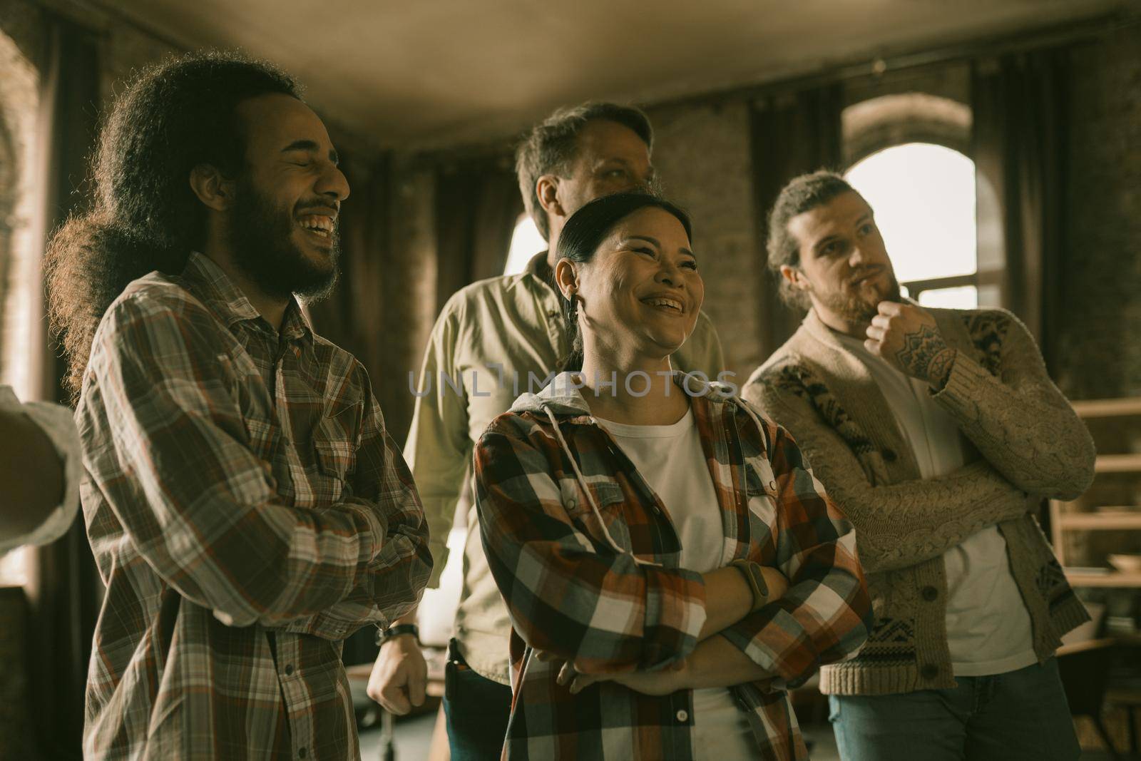 Diverse Group Of Students Or Freelancers Are Looking At Something Hanging On Office Wall, Selective Focus On Asian Woman And Arab Guy Toothy Laughing In Foreground, Side View