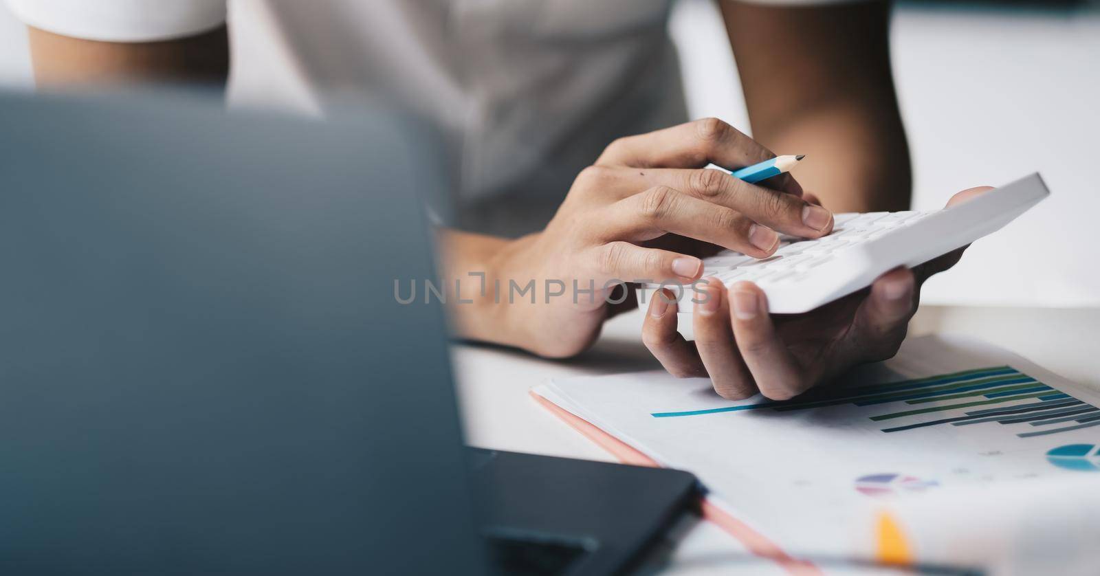 Close up hand of accounting man working on workplace desk in office use calculator calculates monthly expenses, taxes, check bank account balance by nateemee