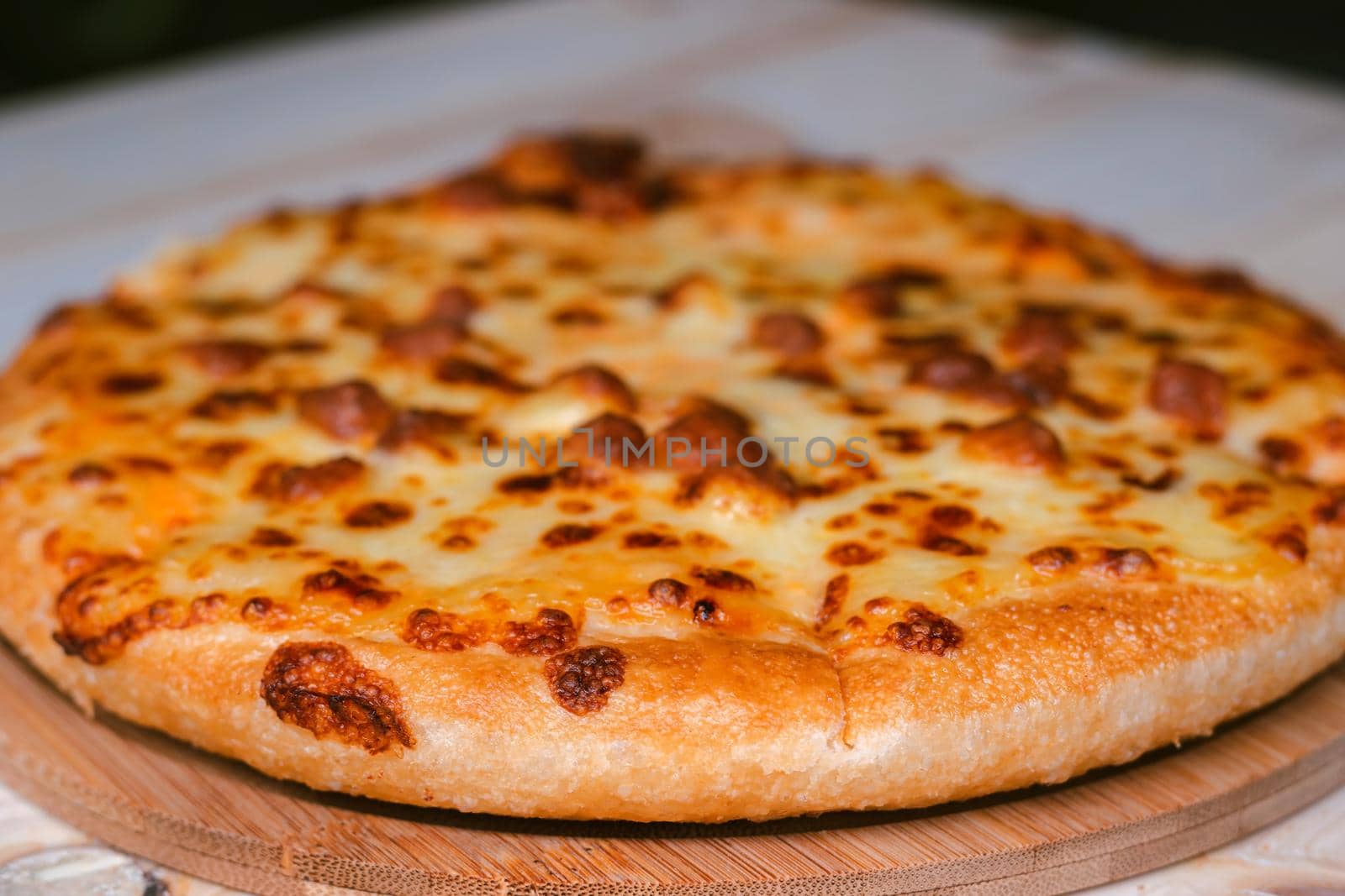 Closeup selective focus of the ready to eat pizza on a wooden tray on a wooden table.