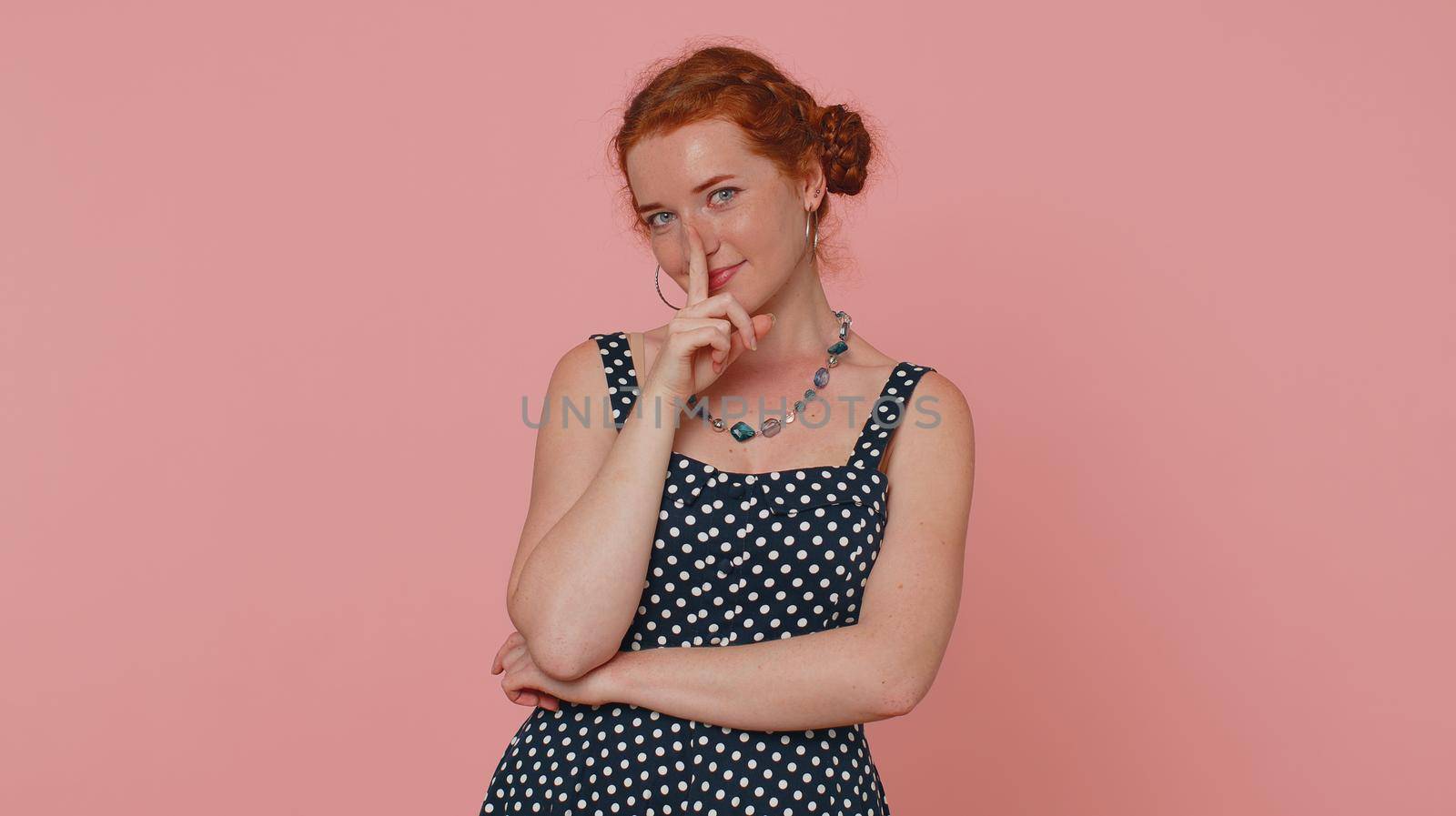 Shh be quiet please. Portrait of redhead woman 20s presses index finger to lips makes silence gesture sign do not tells secret. Young beautiful ginger girl posing isolated on pink studio background