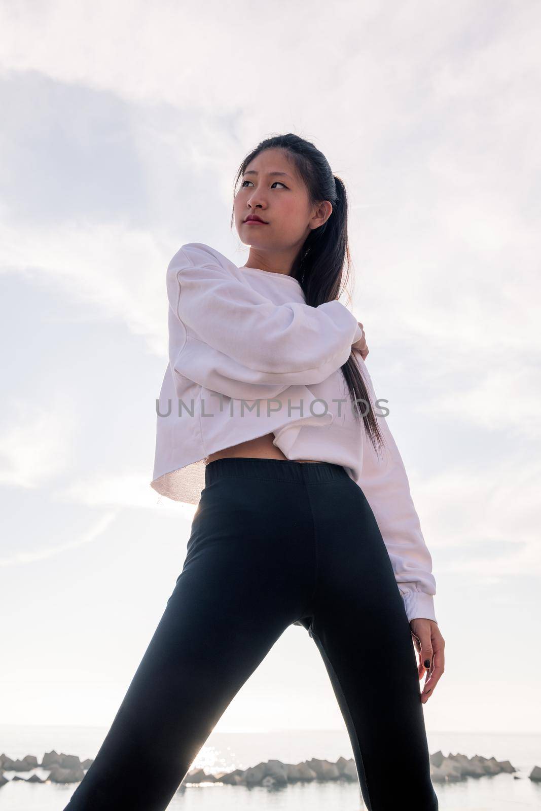 vertical photo of a powerful oriental sportswoman posing confident, concept of sport and healthy lifestyle, copyspace for text