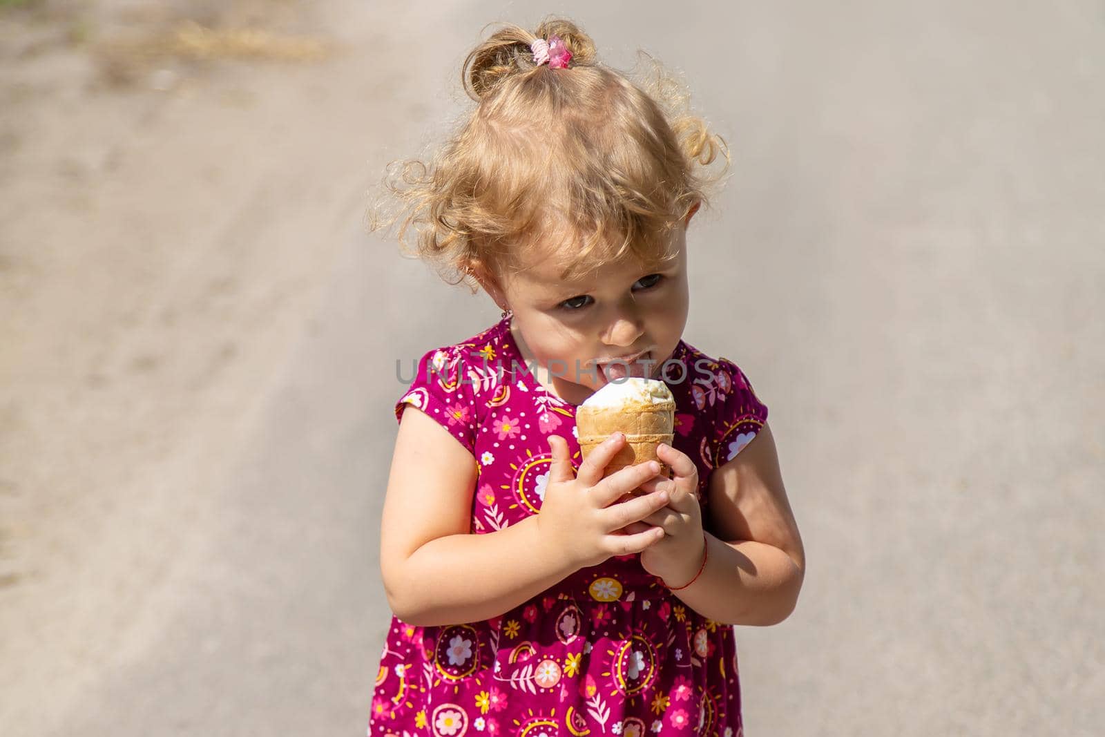 The child eats ice cream on the street. Selective focus. by yanadjana