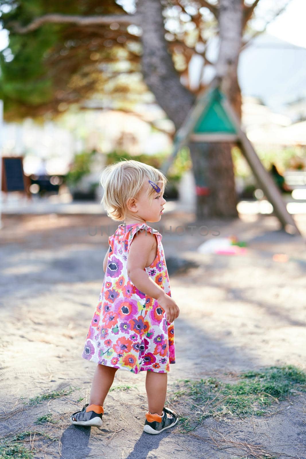 Little girl stands on the playground and looks away. High quality photo