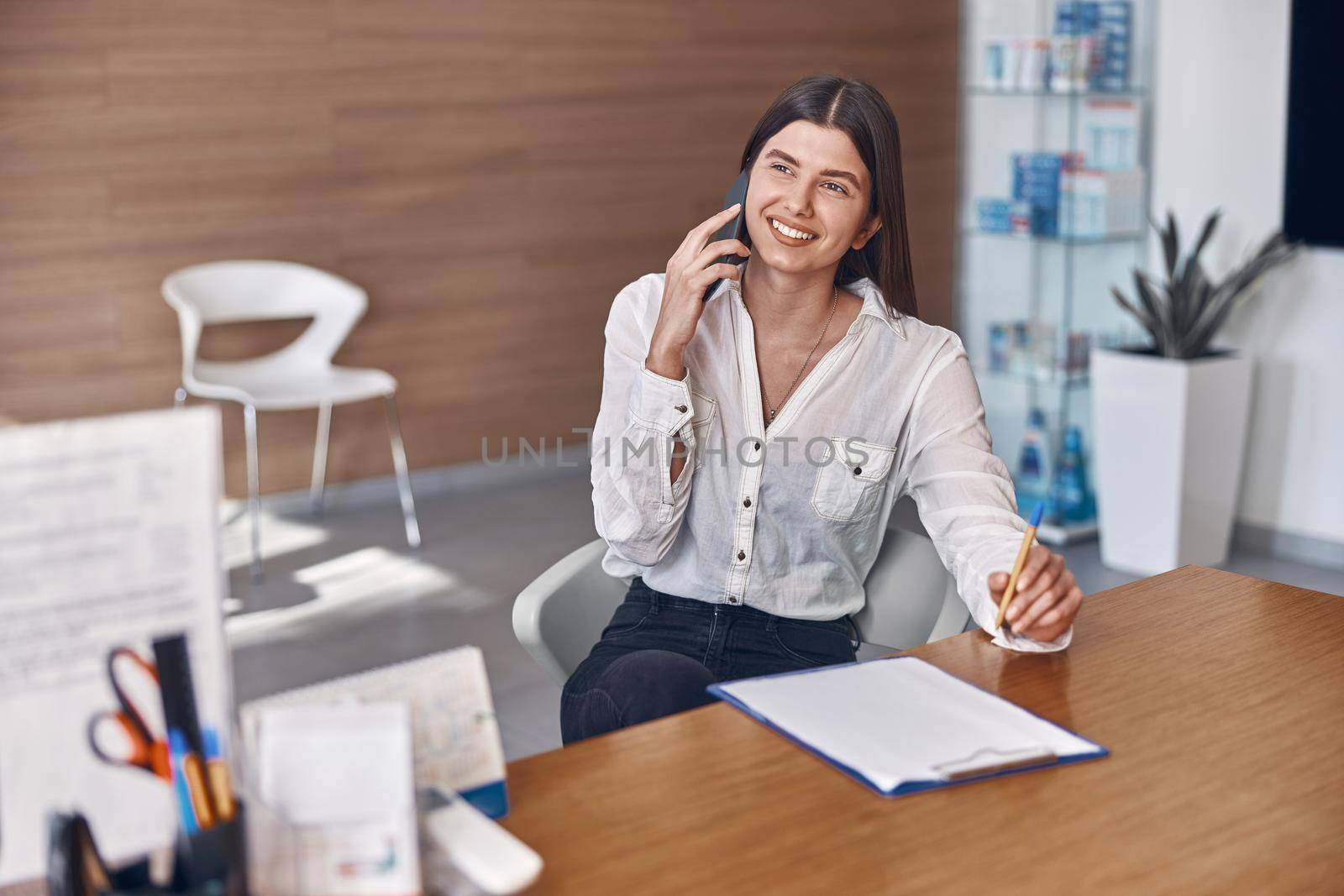 Happy smiling caucasian woman with phone and documents in modern clinic reception