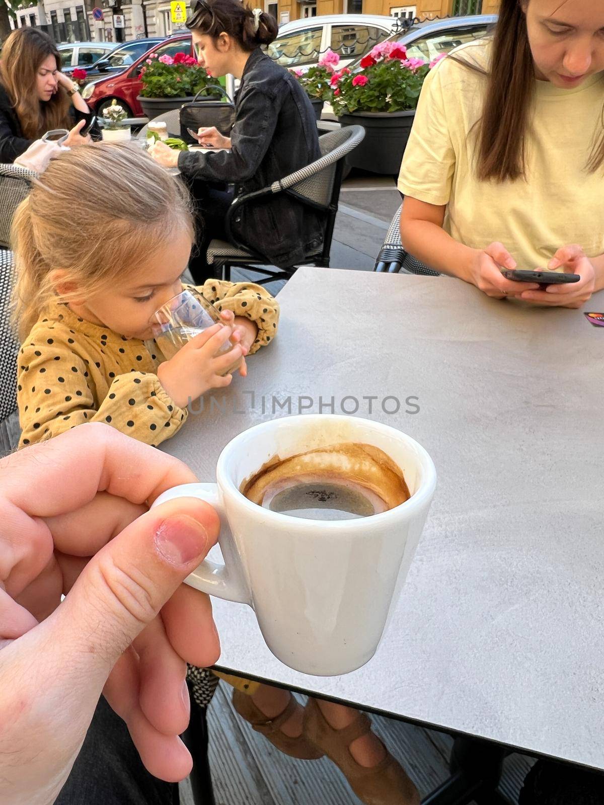 Cup of coffee in a man hand at a table in a restaurant by Nadtochiy