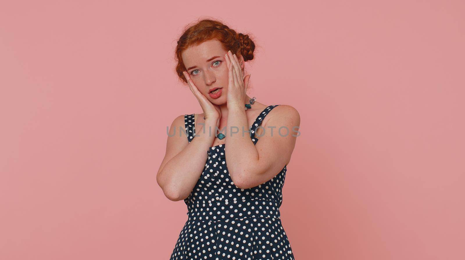 Woman feeling hopelessness and loneliness, nervous breakdown, loses becoming surprised by lottery results, bad fortune, loss, unlucky news. Ginger girl with freckles isolated on pink studio background
