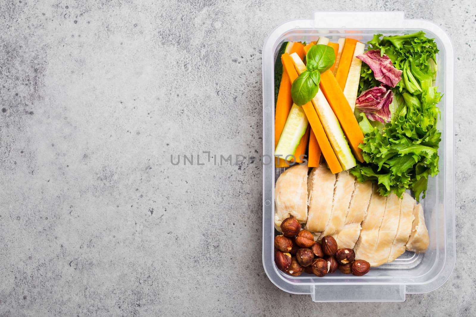 Healthy food lunchbox for office or school: chicken fillet, carrot, cucumber sticks, salad. Preparation and packaging of meal to support balanced lifestyle or diet, stone background, copy space