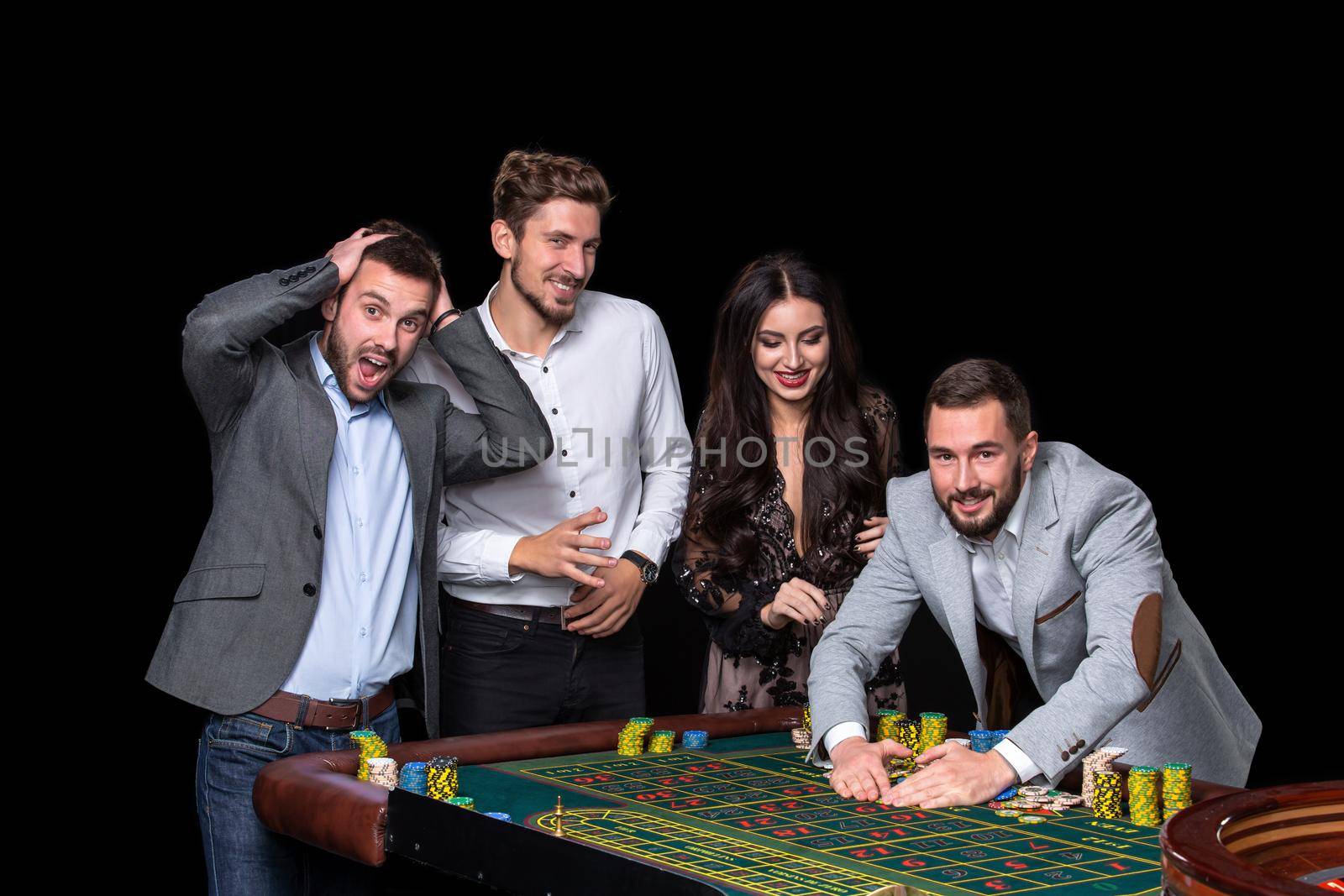 Upper class friends gambling in a casino. Roulette. Black background