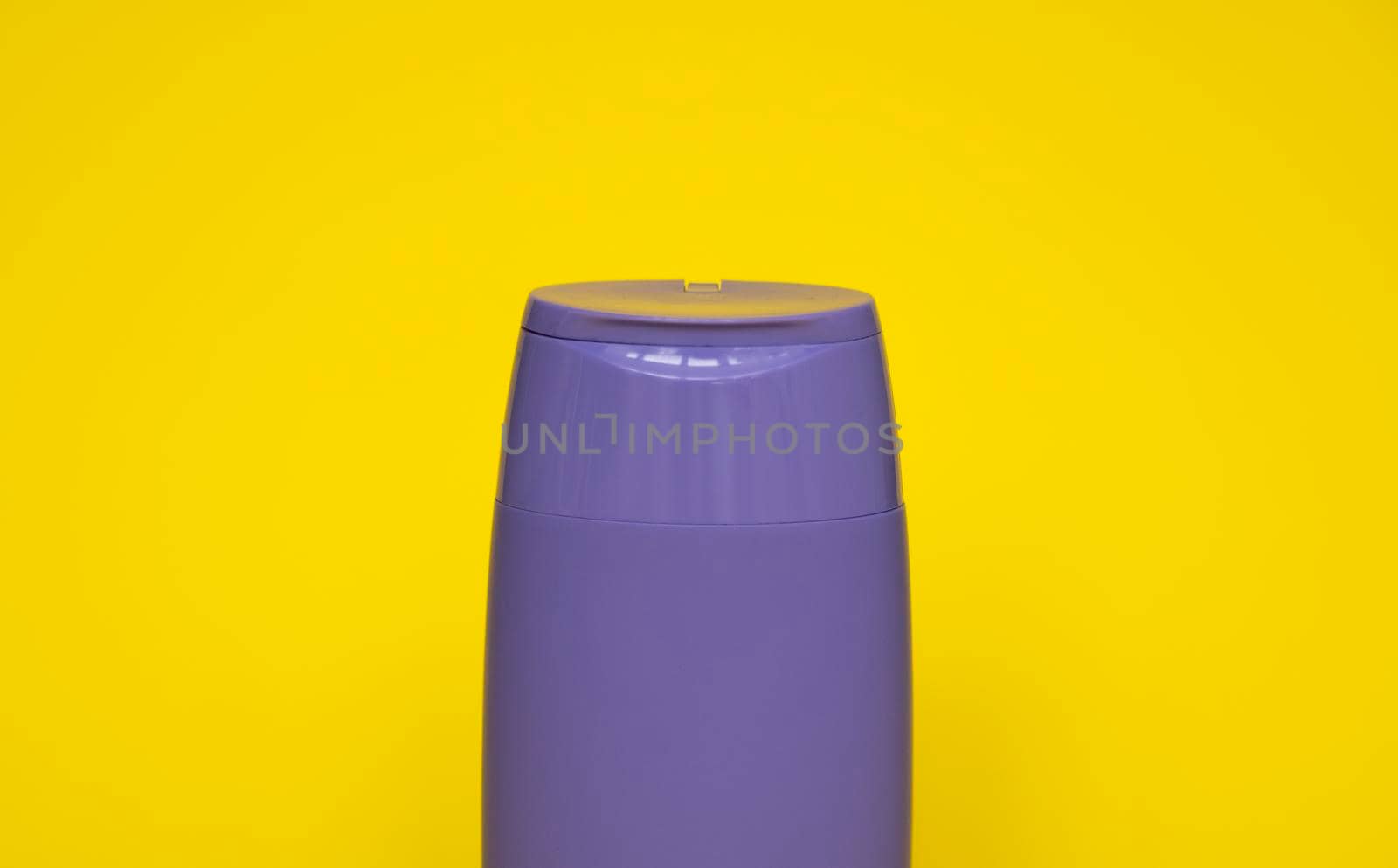 Violet plastic shampoo bottle isolated on yellow background. Skin care lotion. Bathing essential product. Shampoo bottle. Bath and body lotion. Fine liquid hand wash