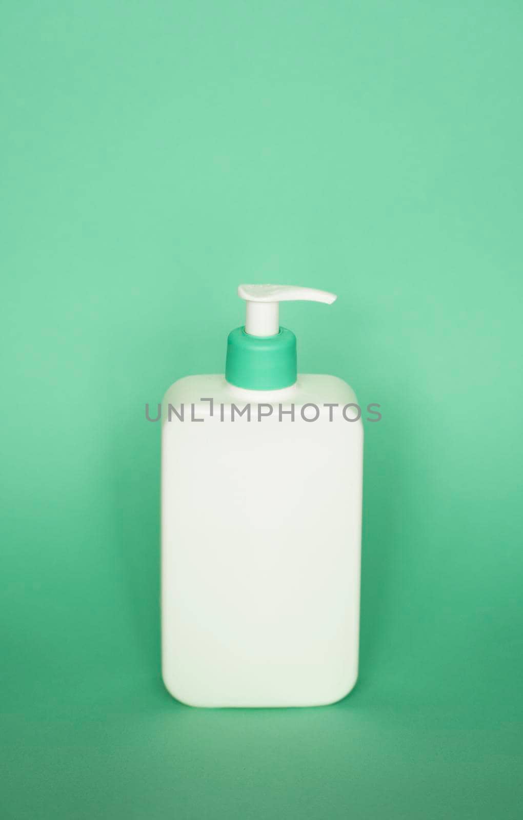 White plastic soap dispenser pump bottle isolated on green background. Skin care lotion. Bathing essential product. Shampoo bottle. Bath and body lotion. Fine liquid hand wash. Bathroom accessories. by vovsht