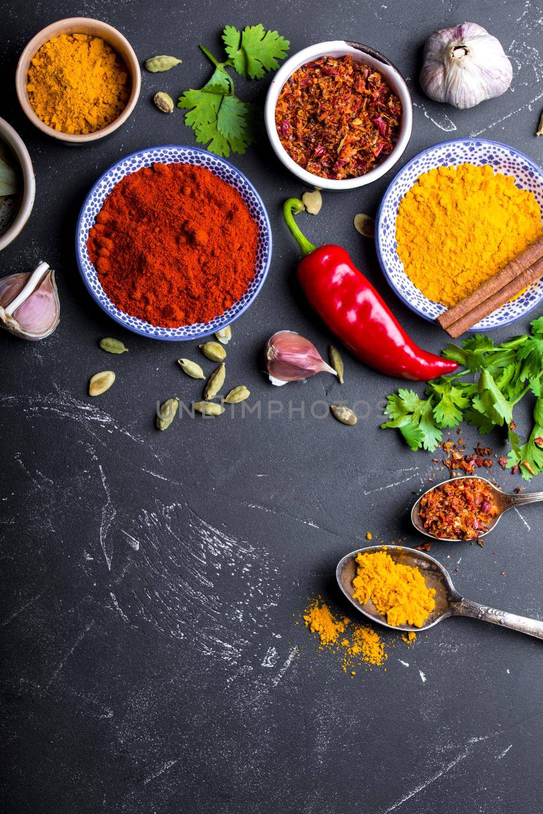 Set of Indian food cooking ingredients. Traditional Indian assorted spices and herbs. Curry, turmeric, cardamom, garlic, pepper, cilantro, cinnamon. Preparing exotic meal. Top view, close up