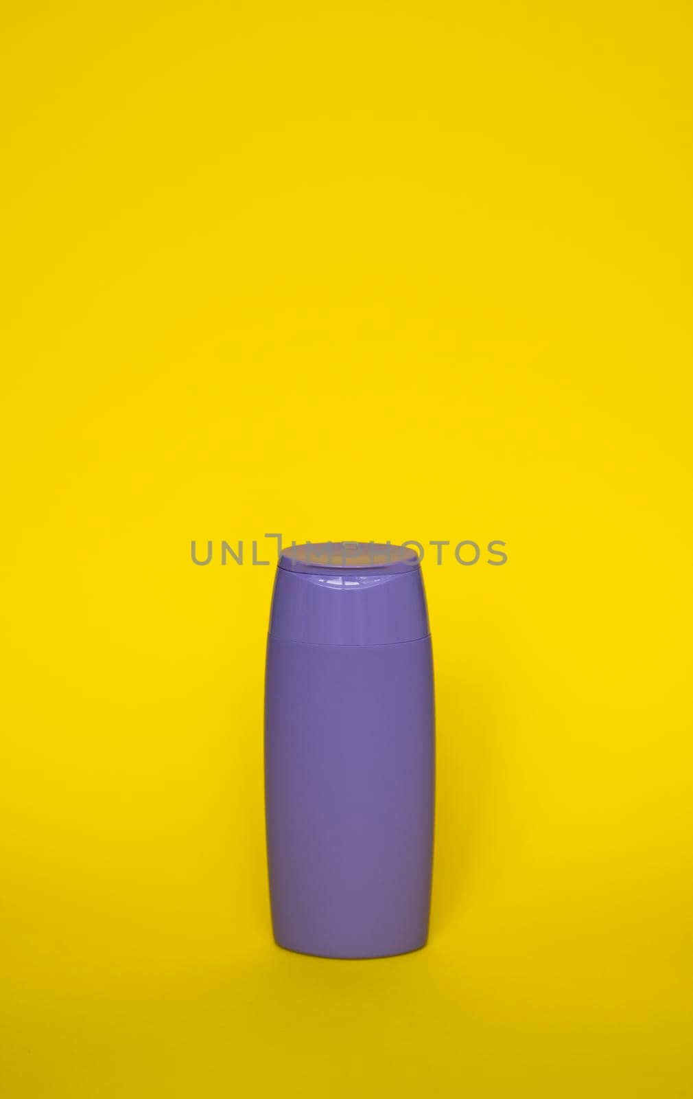 Violet plastic shampoo bottle isolated on yellow background. Skin care lotion. Bathing essential product. Shampoo bottle. Bath and body lotion. Fine liquid hand wash