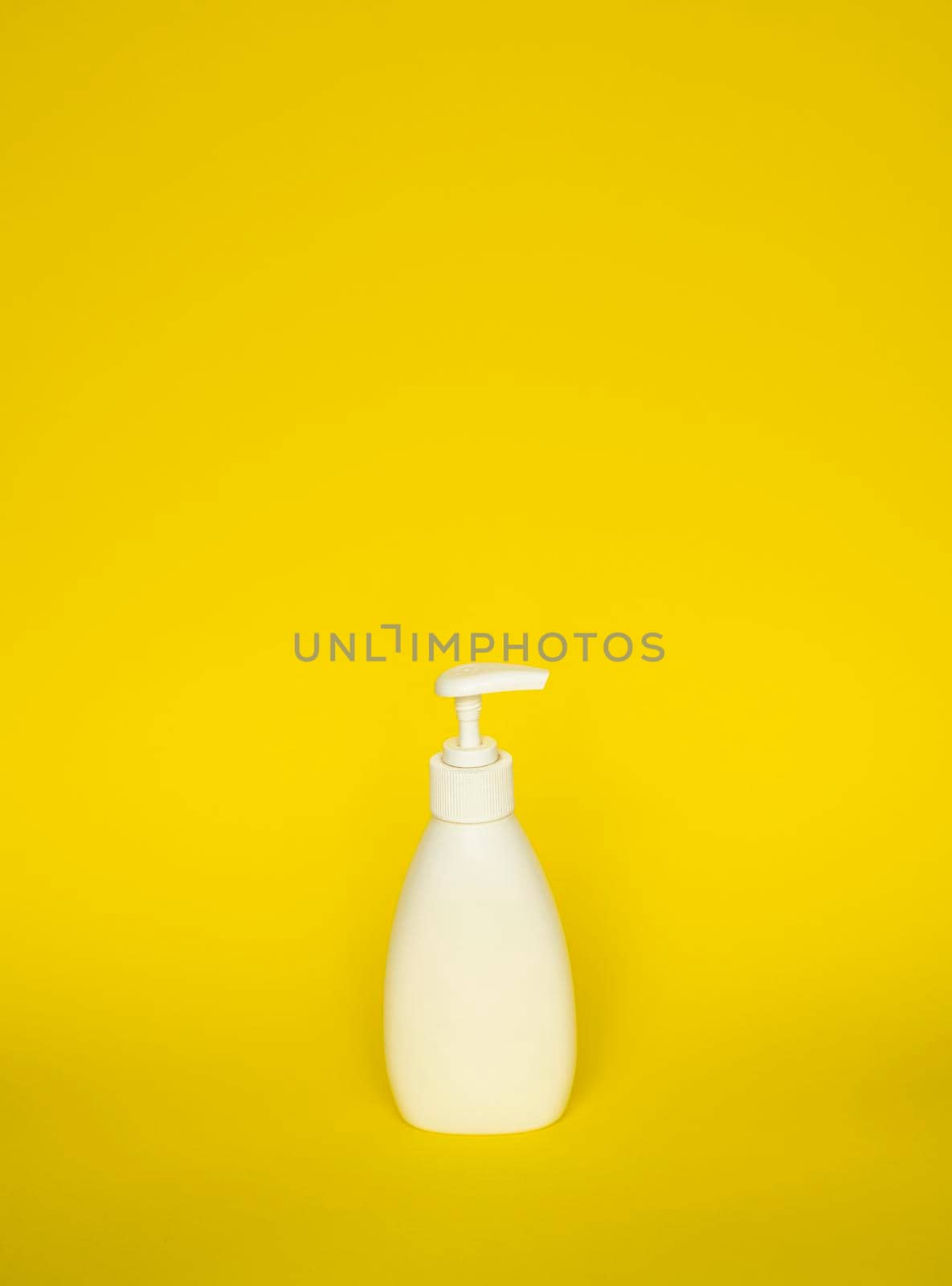 White plastic soap or shampoo dispenser pump bottle isolated on yellow background. Skin care lotion. Bathing essential product. Shampoo bottle. Bath and body lotion. Fine liquid hand wash
