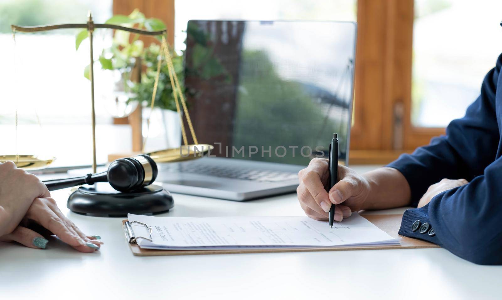 Justice and Law concept. Legal counsel presents to the client a signed contract with gavel and legal law or legal having team meeting at law firm in background.