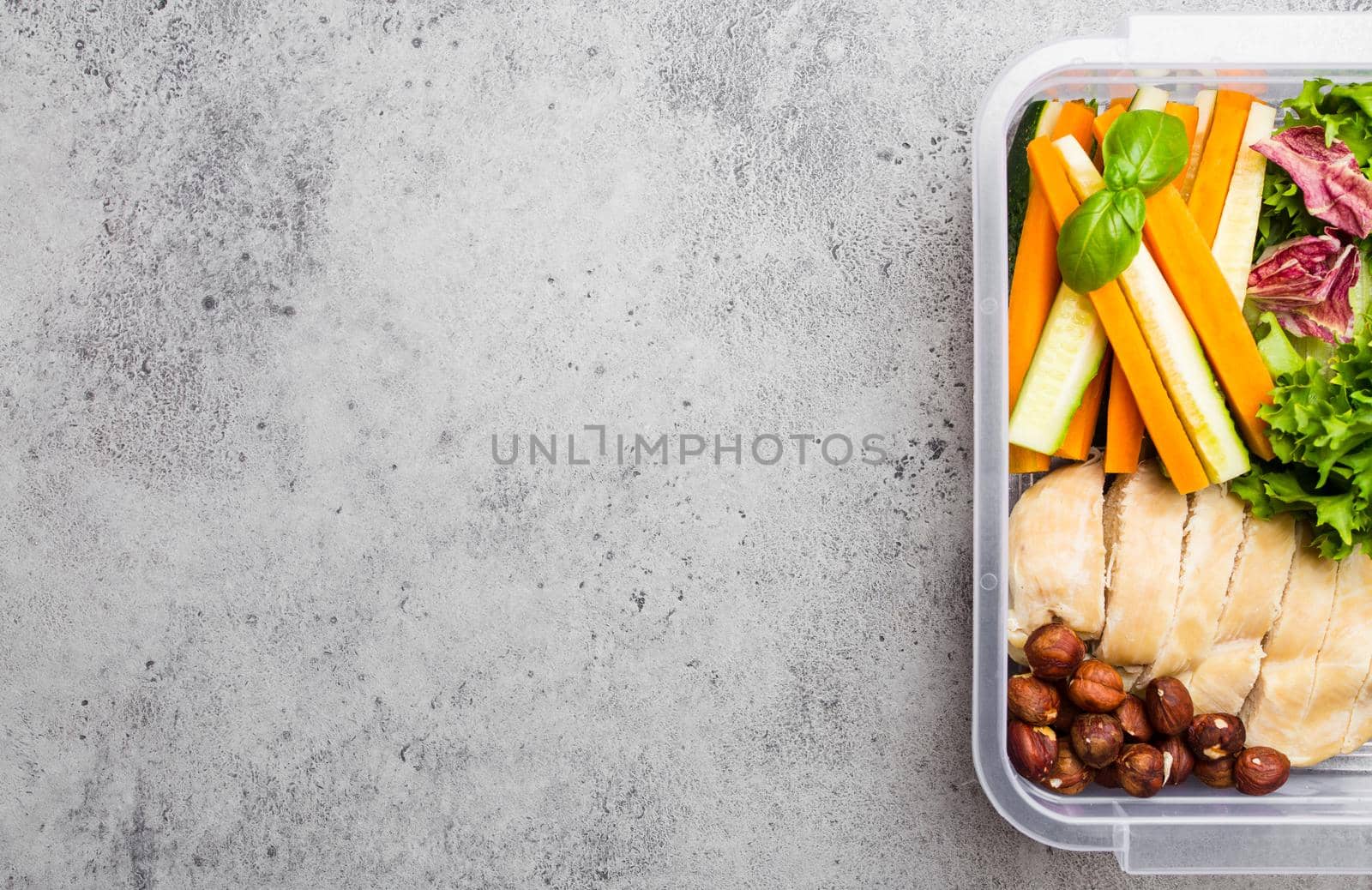 Healthy food lunchbox for office or school: chicken fillet, carrot, cucumber sticks, salad. Preparation and packaging of meal to support balanced lifestyle or diet, stone background, copy space