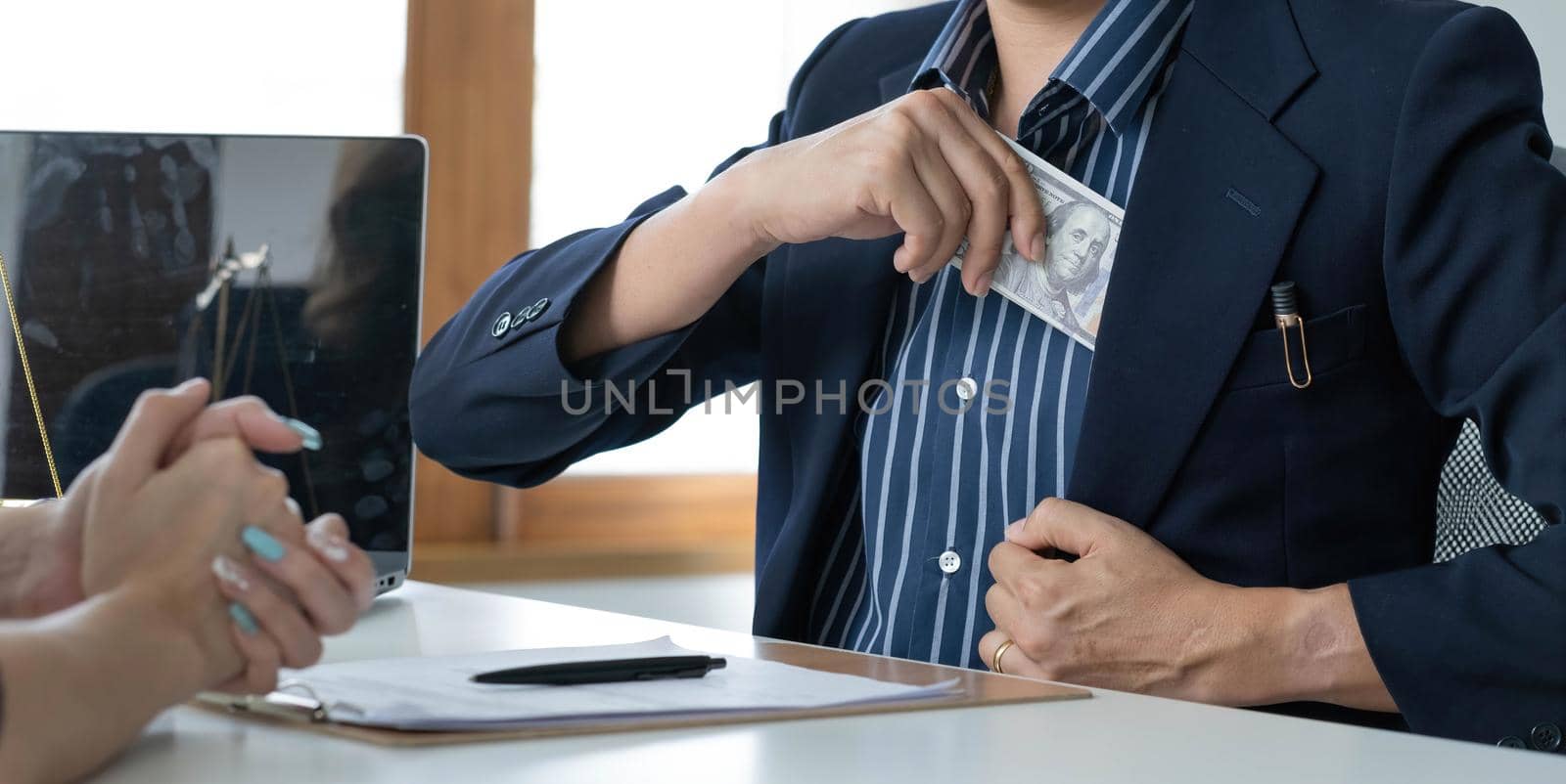 A businessman take a dollar money banknote into his suit pocket. Corruption and bribery concept. cropped image by wichayada