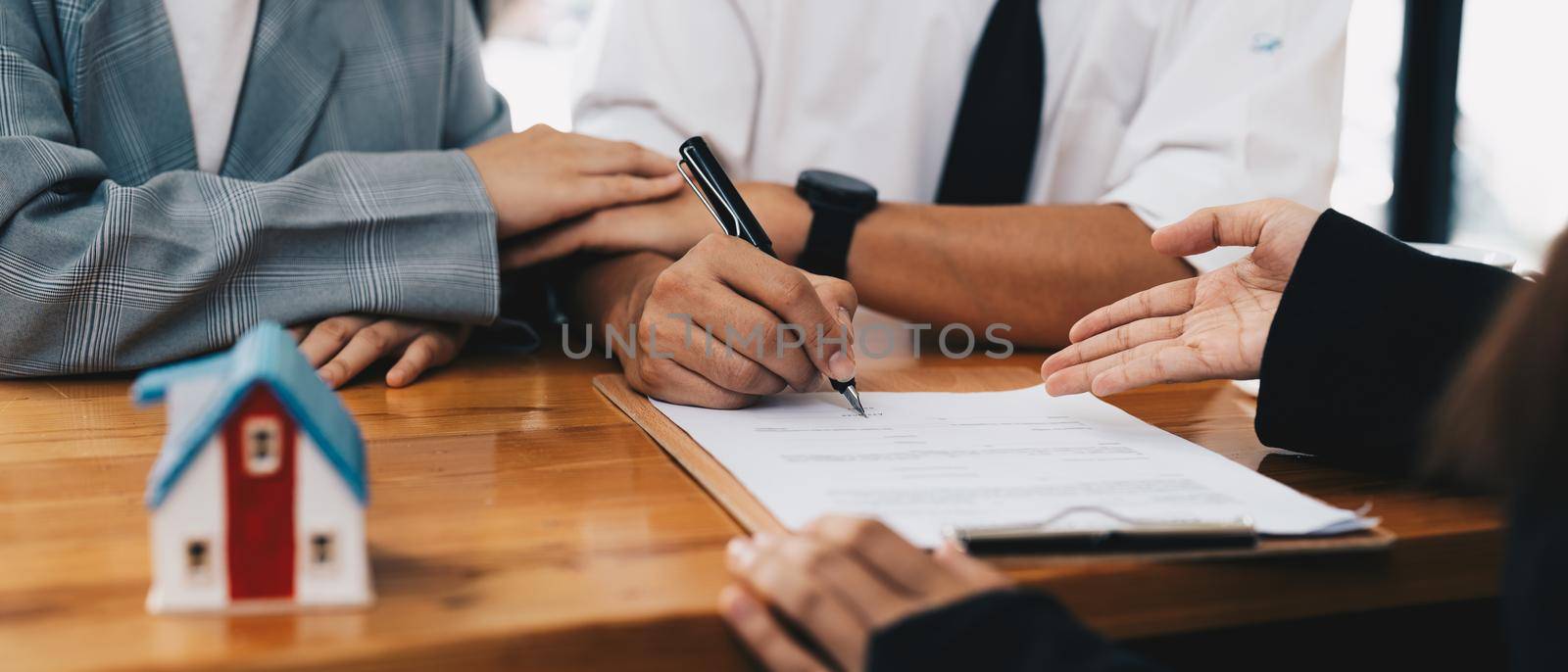 Business woman and young couple signing agreement for buying house. Bank manager and real estate concept. by nateemee