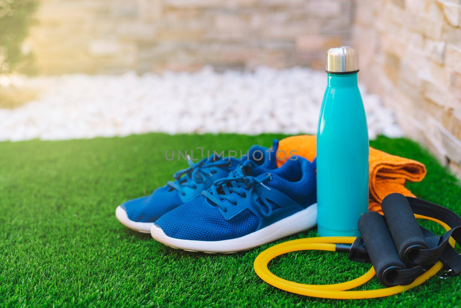 Close-up of objects and accessories for practising sport in a green grass garden. rubber bands for stretching, towel, water bottle. concept of practising sport in the open air. by CatPhotography