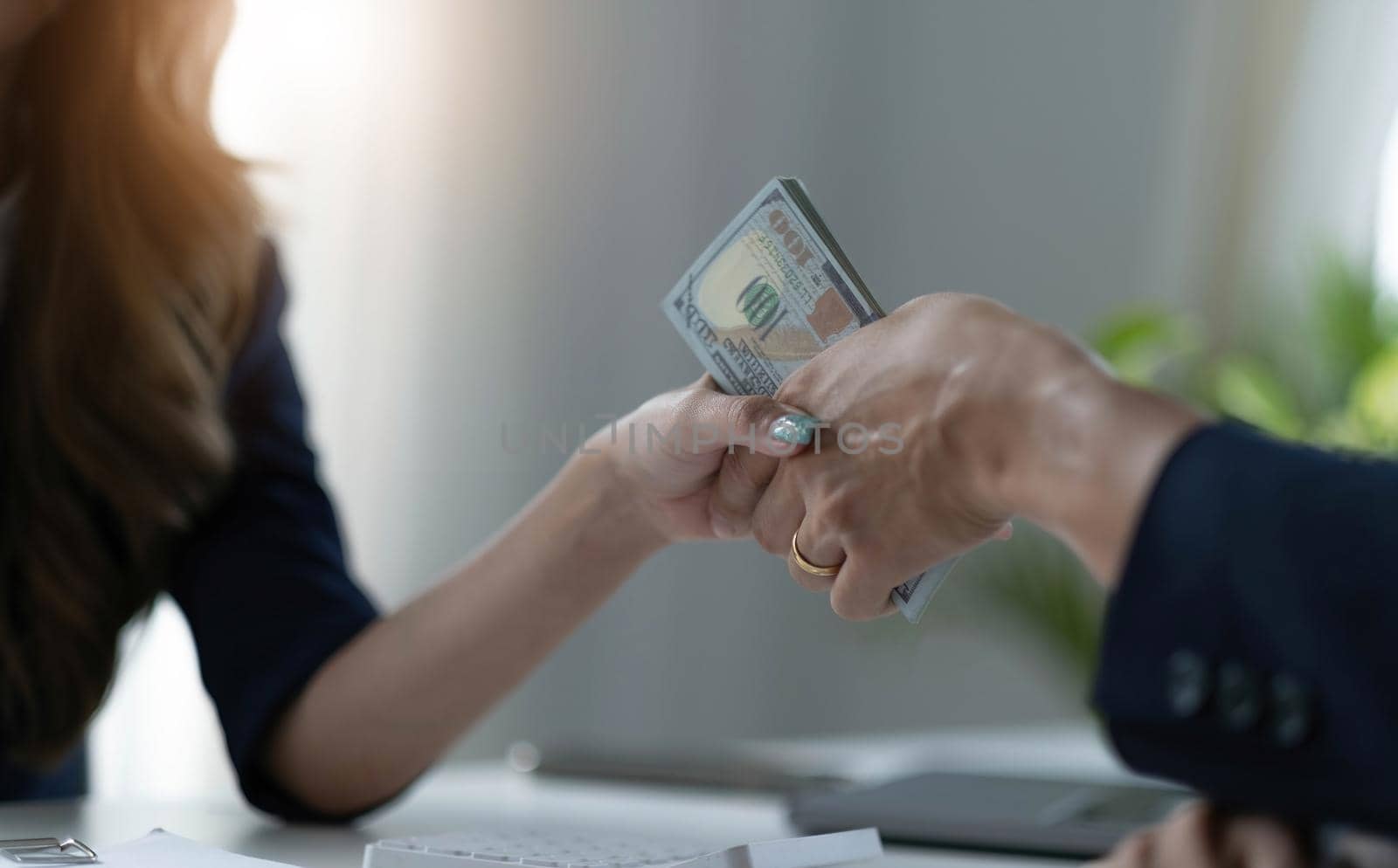 A female lawyer or business legal consultant receives a bribe or tribute from her client in the office. Corruption concept. cropped and close-up image.