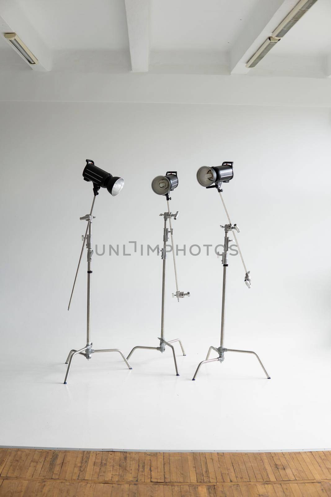 Professional lighting equipment, flashes, c-stands on a cyclorama in modern photo studio. Octabox, stripbox, softbox, buety plate and other stuff for photography. by vovsht
