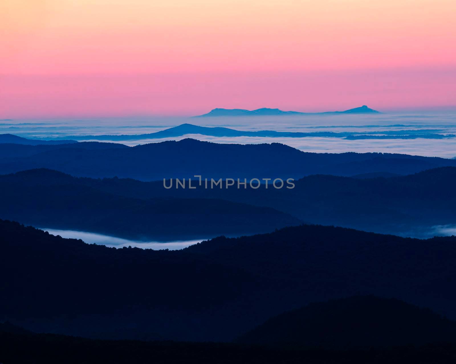 Mountains rise above the clouds in predawn light as seen from the Blue Ridge Parkway in North Carolina.