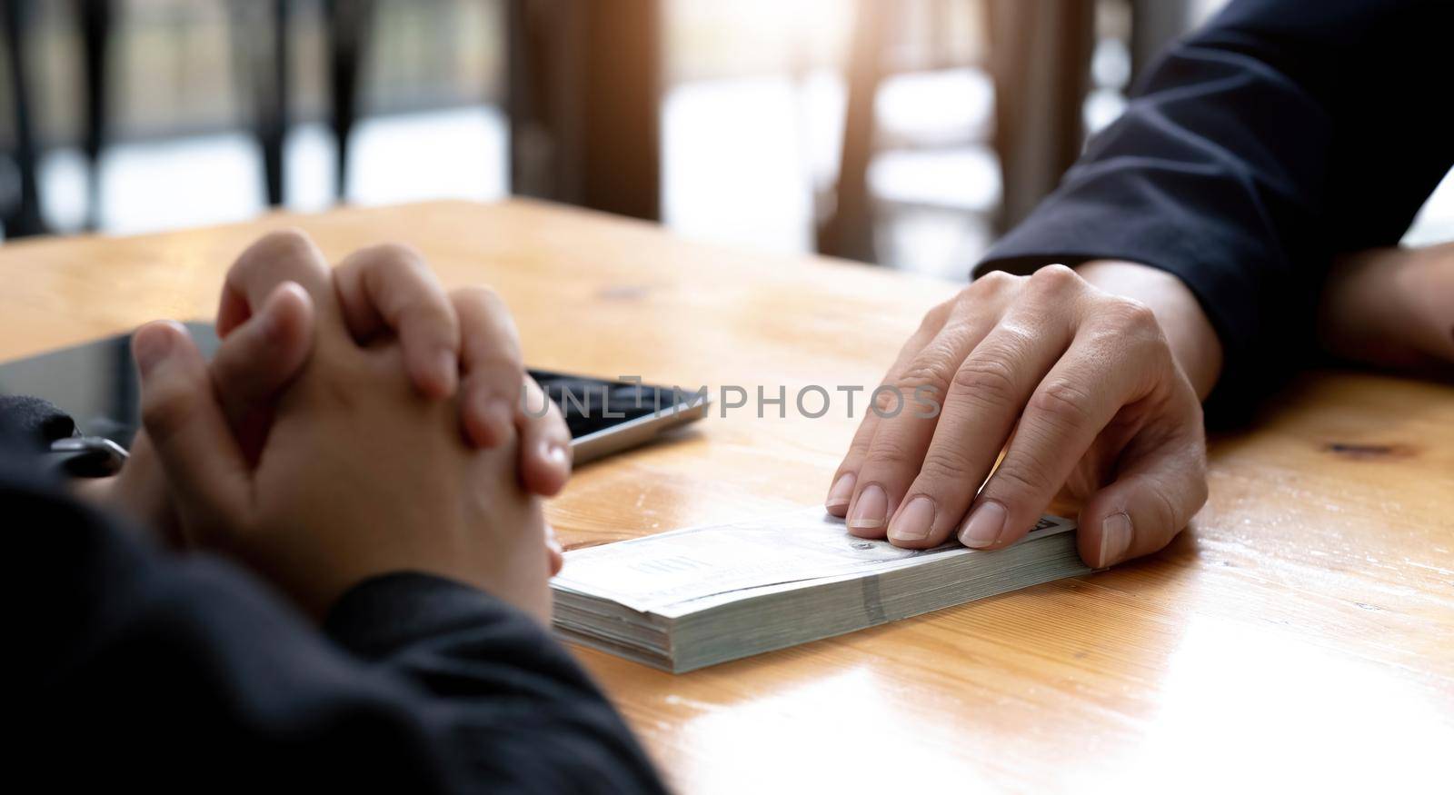 Two businesspeople having a business negotiation meeting in the office, A businessman giving a bribe to his business partner. Cropped and close-up image by wichayada