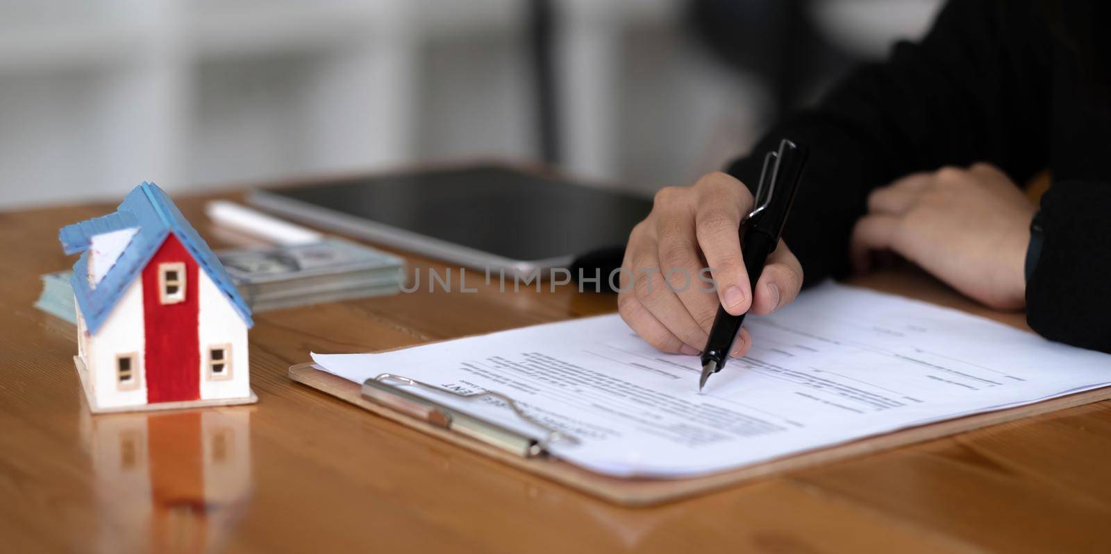 A professional female real estate agent in formal suit at the office desk, checking the rental or property investment contract document. cropped.
