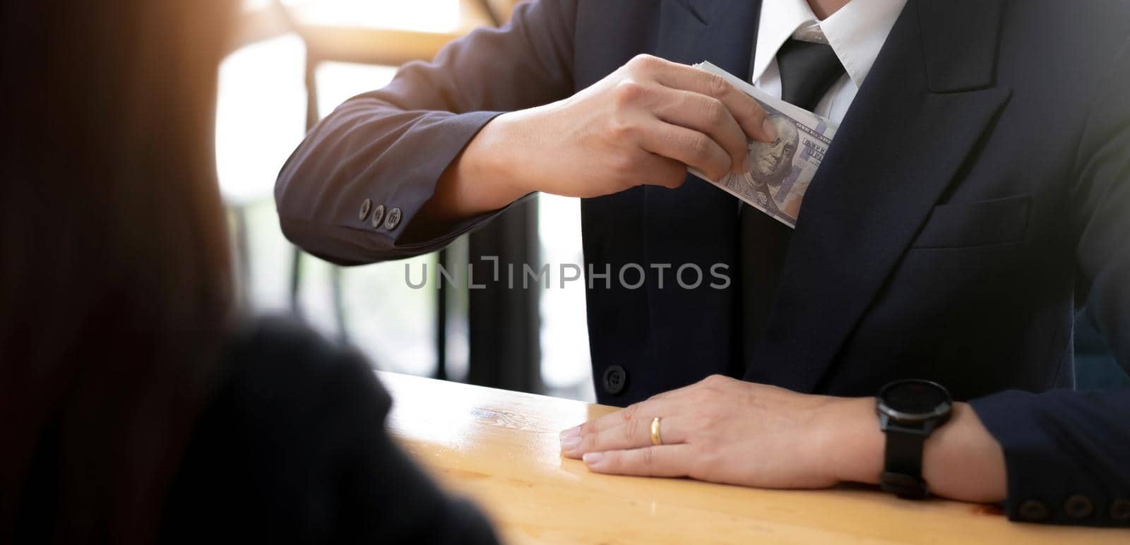 A businessman take a dollar money banknote into his suit pocket. Corruption and bribery concept. cropped image by wichayada