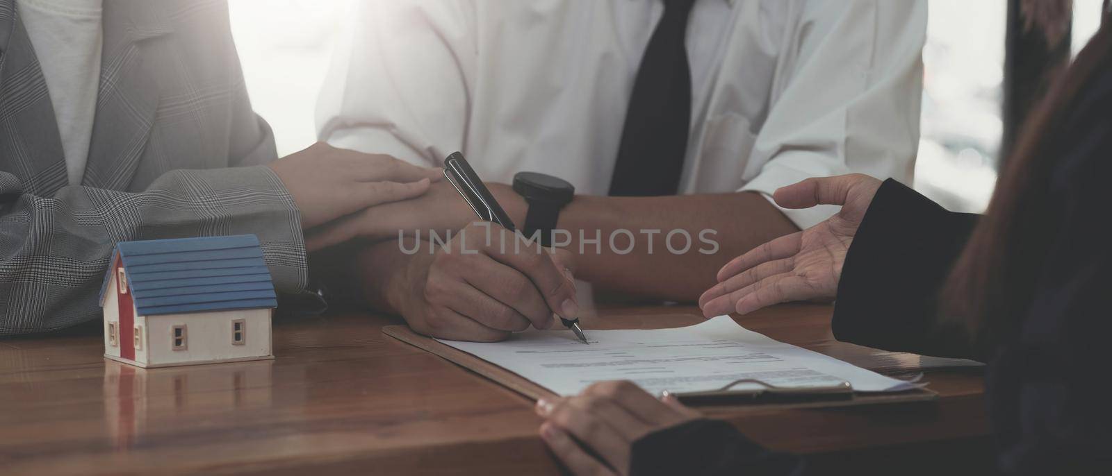 A lovely couple in the meeting with their real estate agent to sign the house contract. Property investment concept. cropped image by wichayada