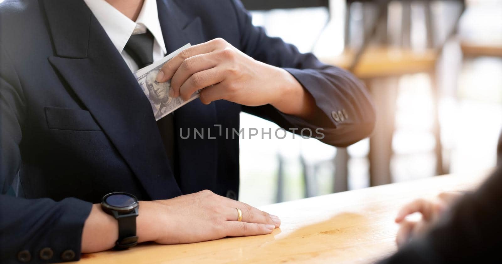 Businessman putting banknotes of dollars in suit pocket. Corruption concept with copy space.