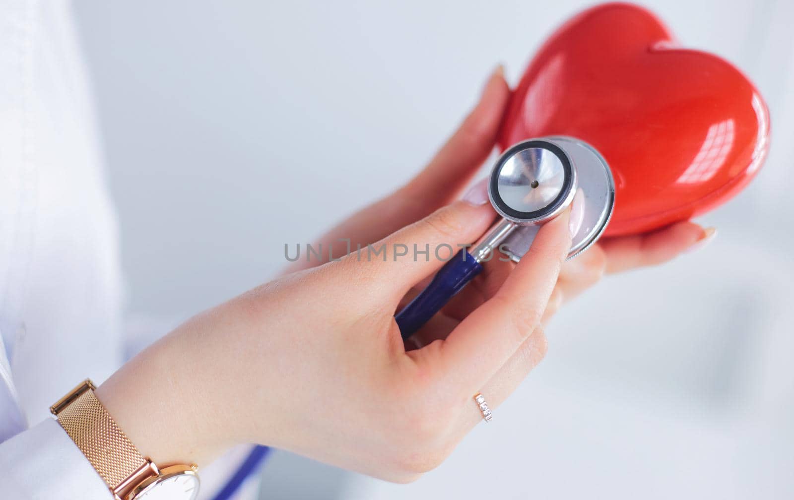 A doctor with stethoscope examining red heart, isolated on white background by lenets