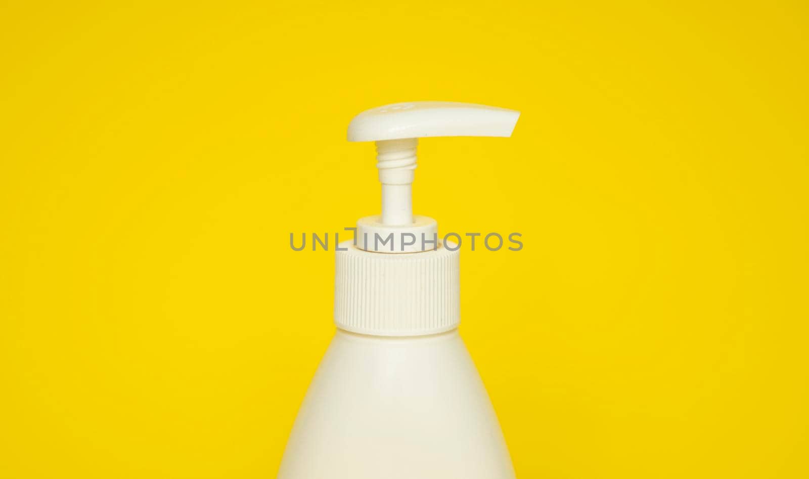 White plastic soap or shampoo dispenser pump bottle isolated on yellow background. Skin care lotion. Bathing essential product. Shampoo bottle. Bath and body lotion. Fine liquid hand wash