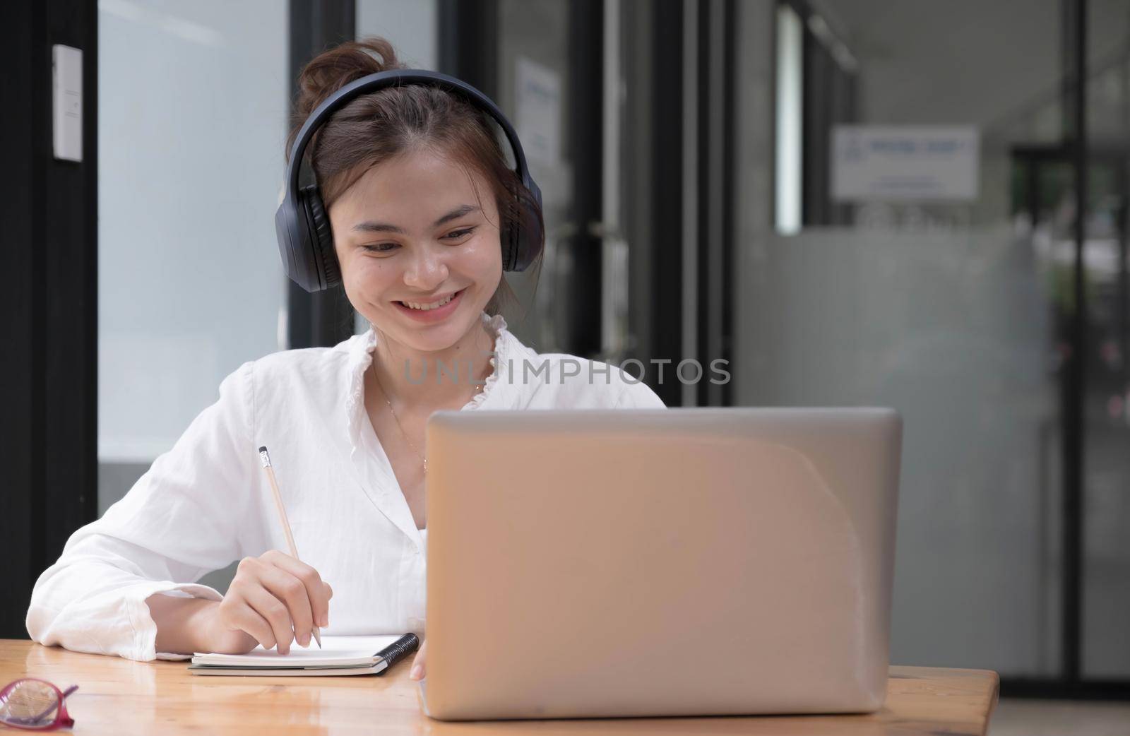 close up of Student learning online class by using laptop computer and writing notebook at workplace, E learning and online working concept..