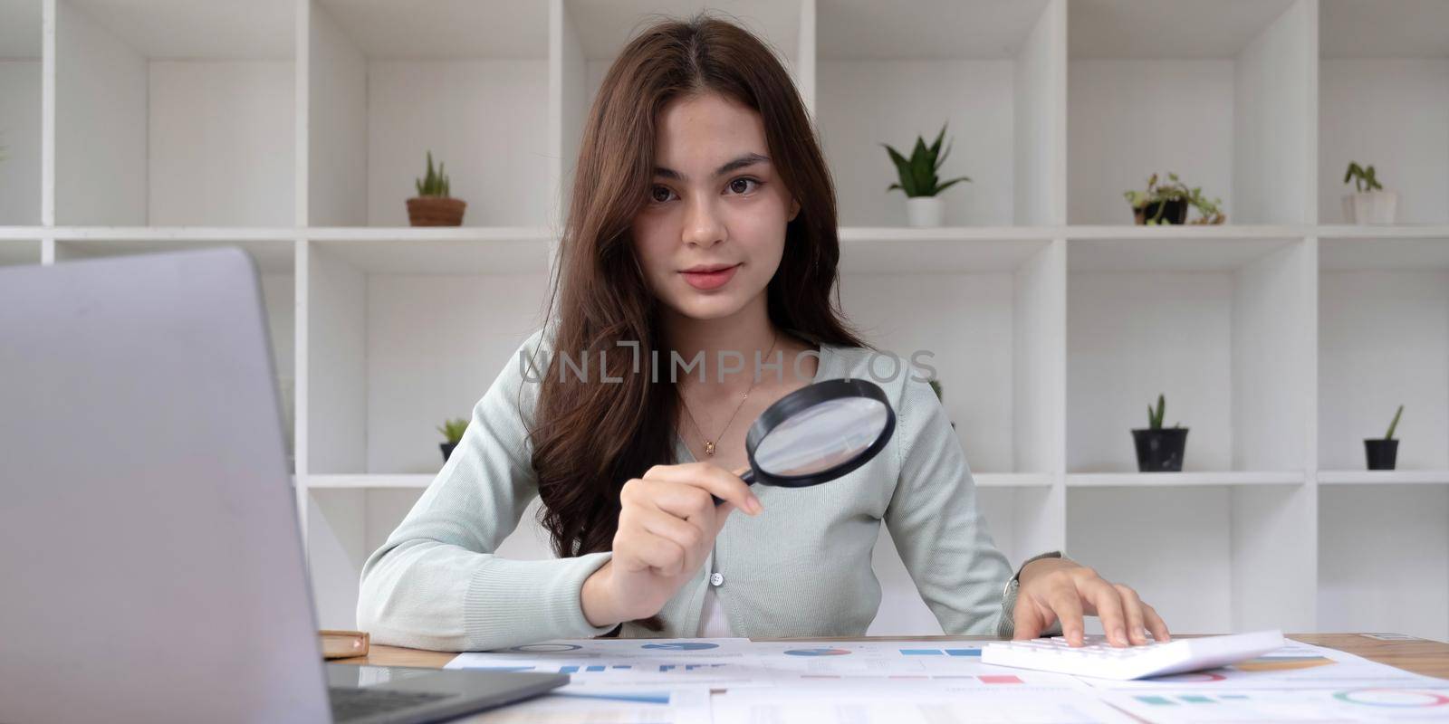 Tax inspector and financial auditor looking through magnifying glass, inspecting company financial papers, documents and reports by wichayada