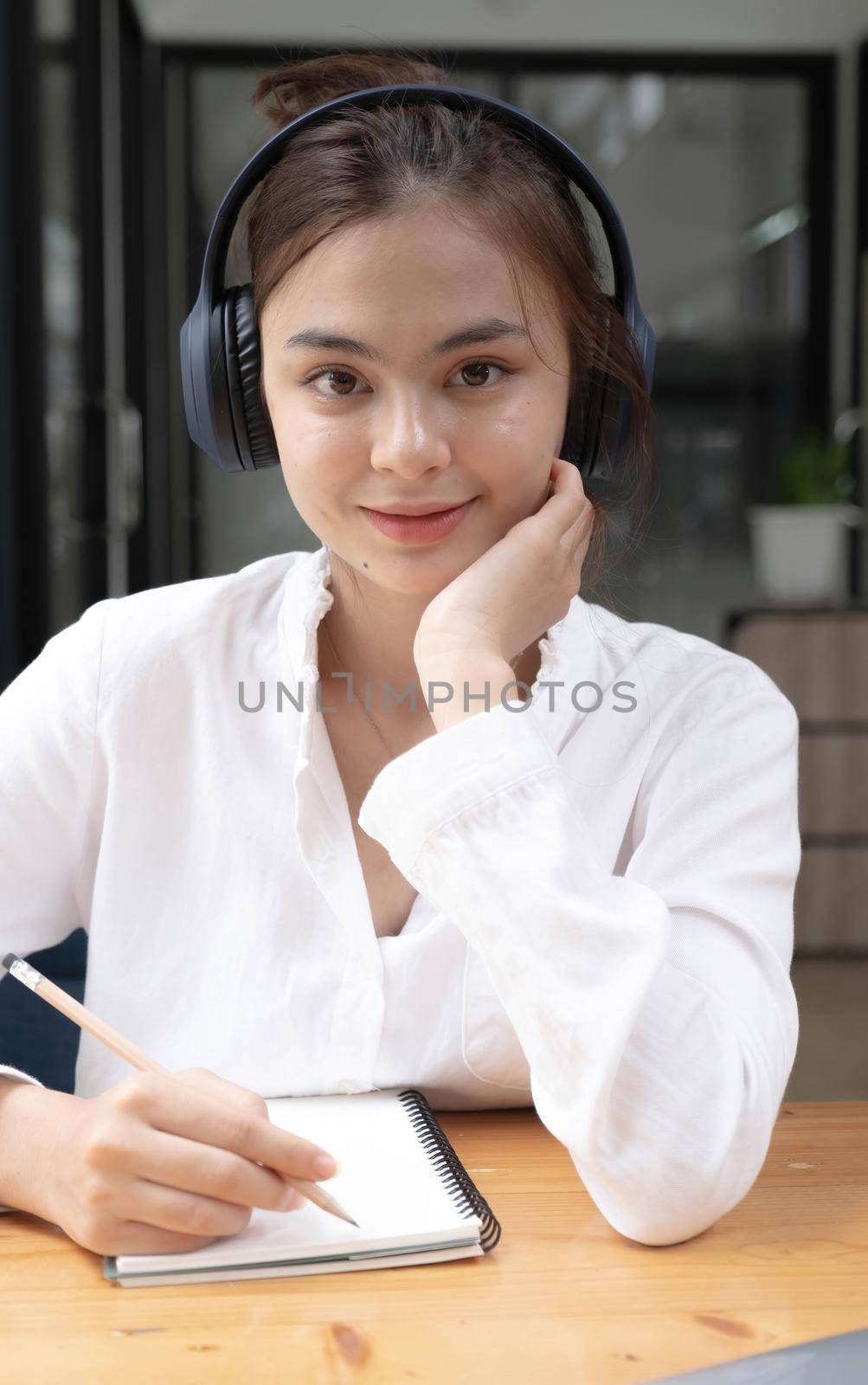 Image of a young woman studying online using a tablet. Looking at the camera..